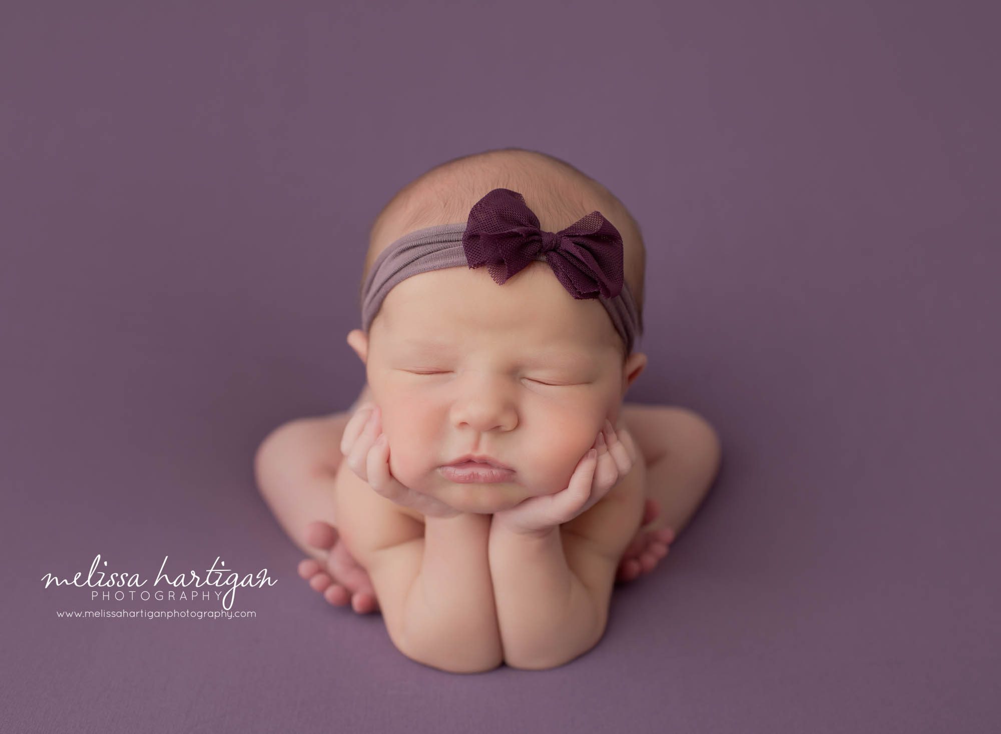 Baby girl posed on purple backdrop with purple bow headband