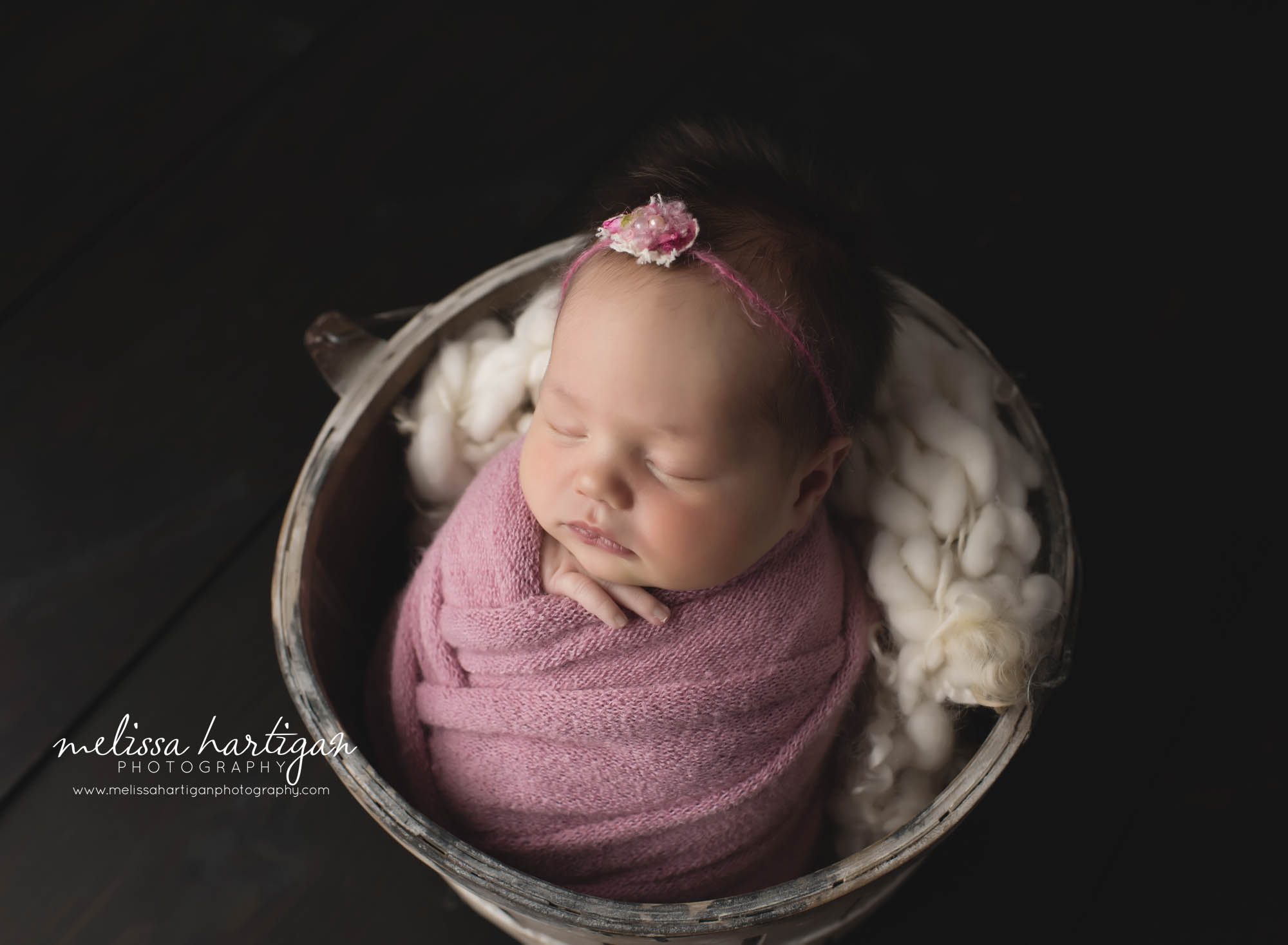 newborn baby girl posed in bucket with pink wrap