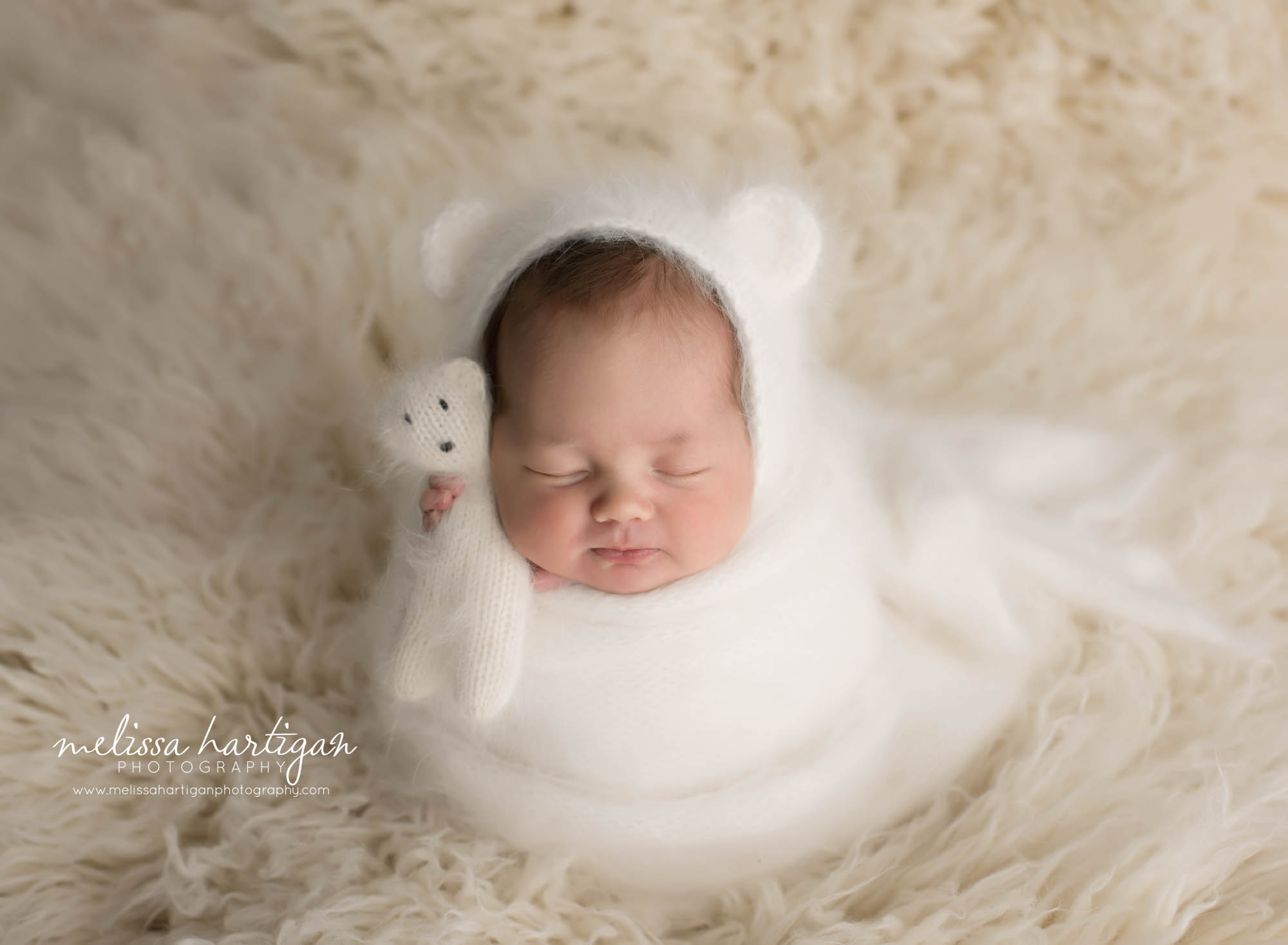 newborn baby girl wrapped in cream knitted wrap with knitted matching bonnet and teddy bear