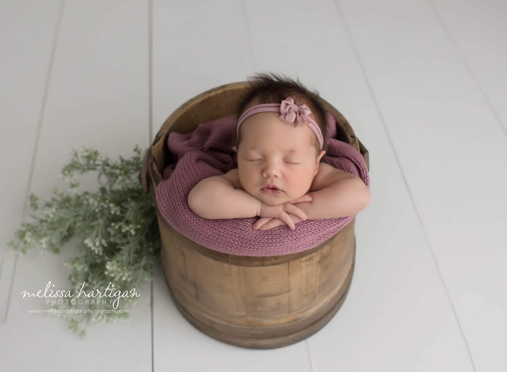 newborn baby girl posed in barrel with pink bow headband east lyme CT baby photographers