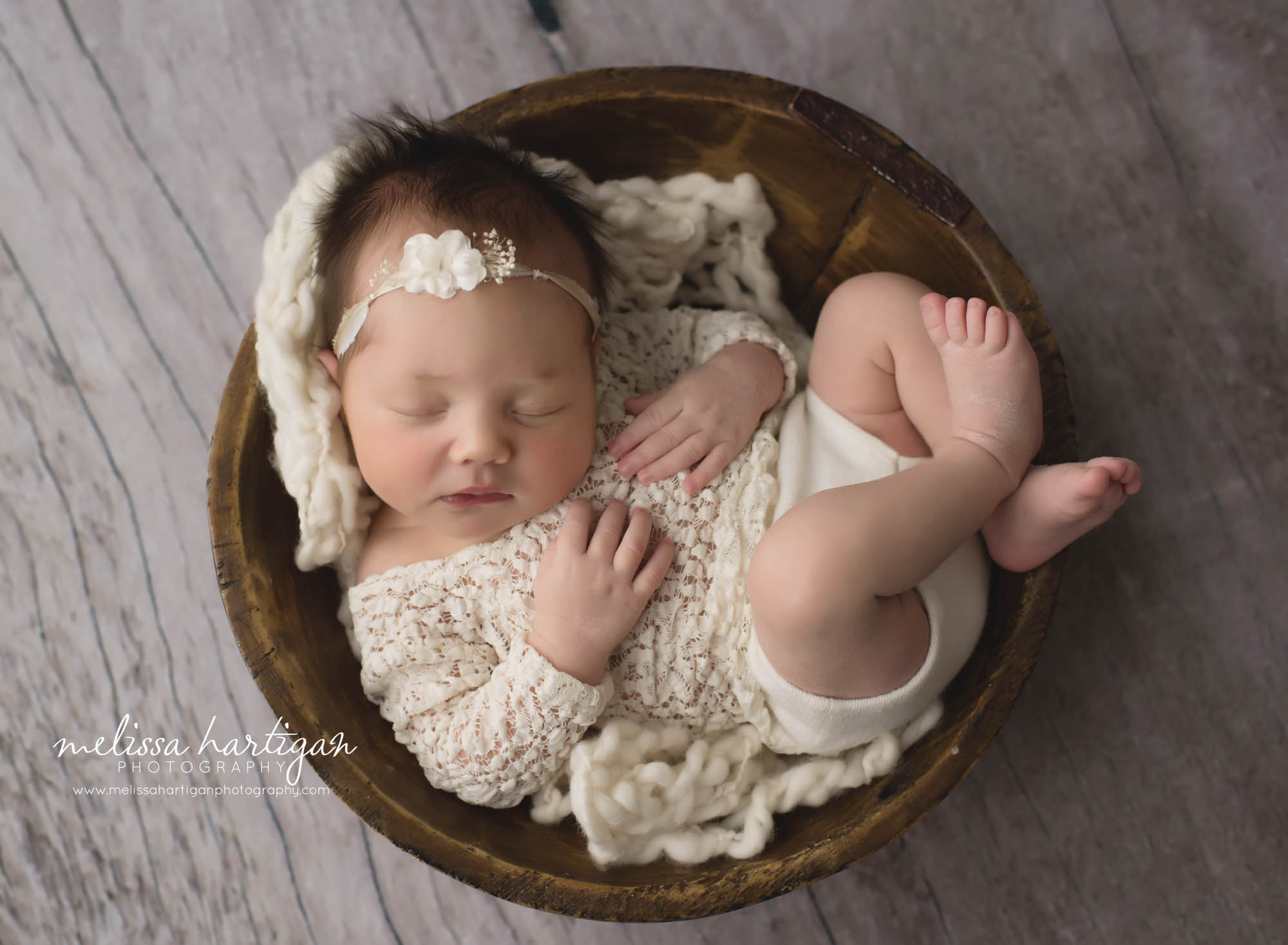 newborn baby girl posed in wooden bowl with cream coloured outfit