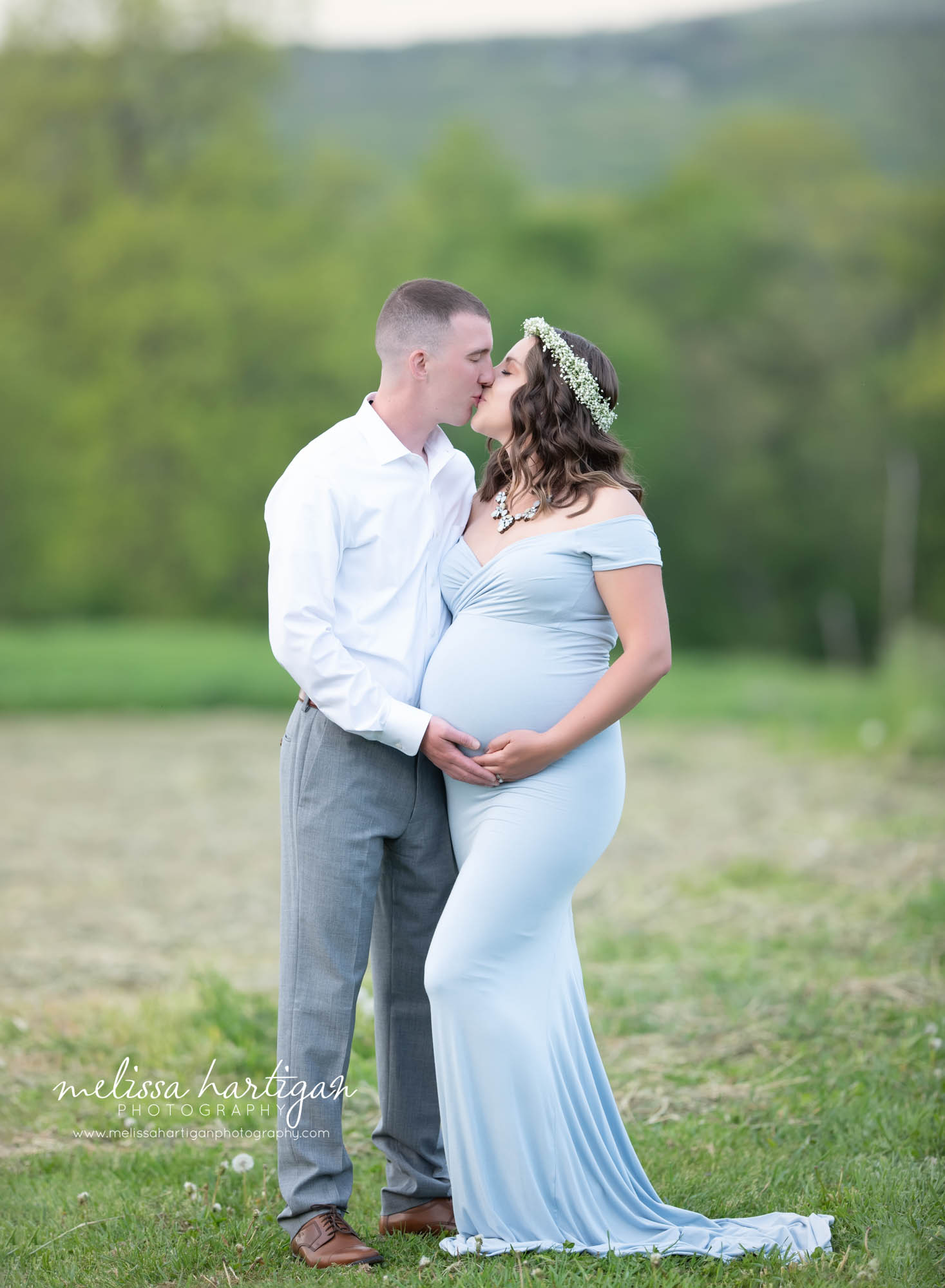mom dad holding baby bump mom wearing long light blue maternity gown with baby's breath flower wreath Massachusetts maternity photography
