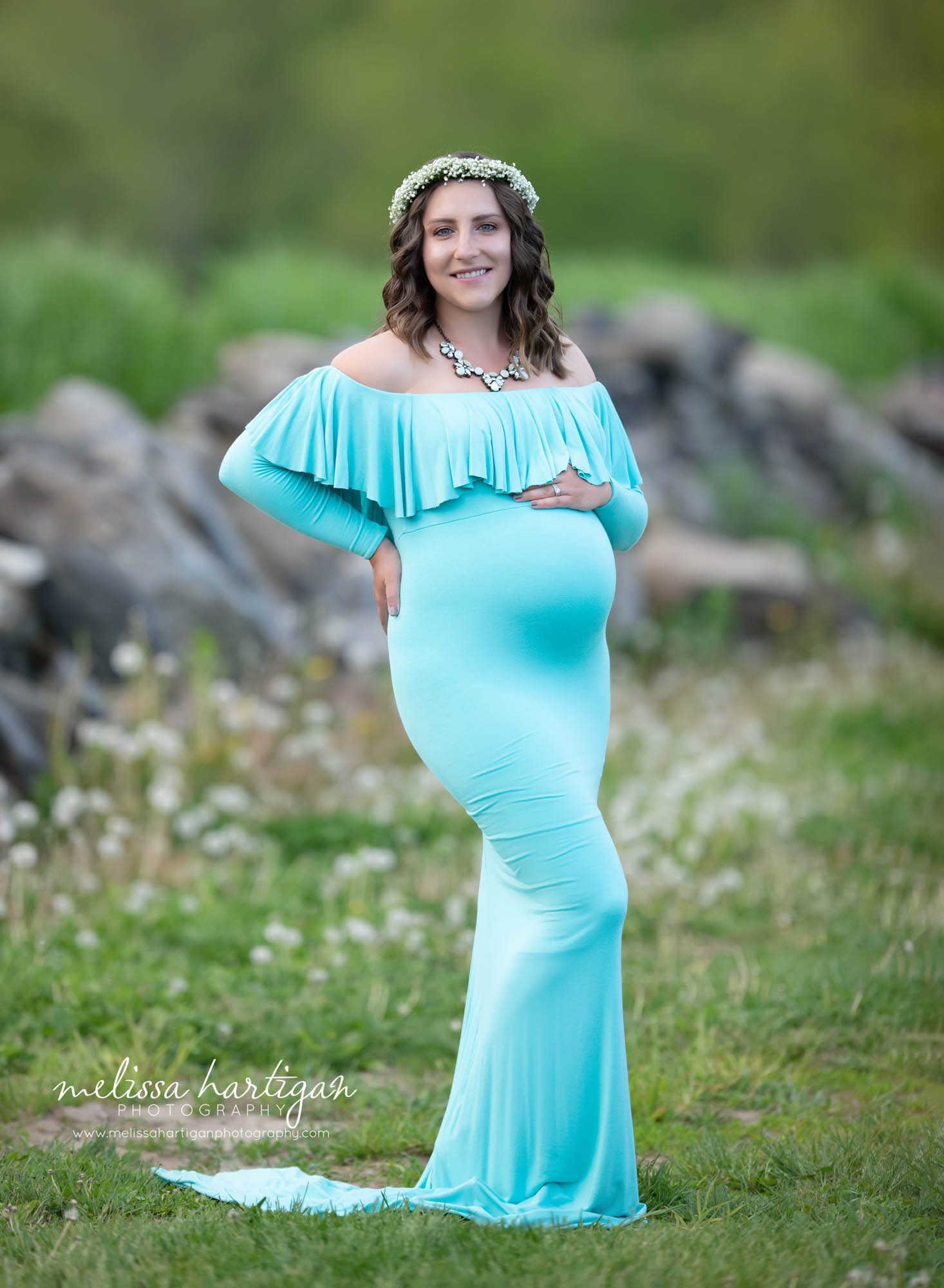 mom holding baby bump wearing bright blue long form fitted maternity gown with ruffles neck line Massachusetts maternity photography