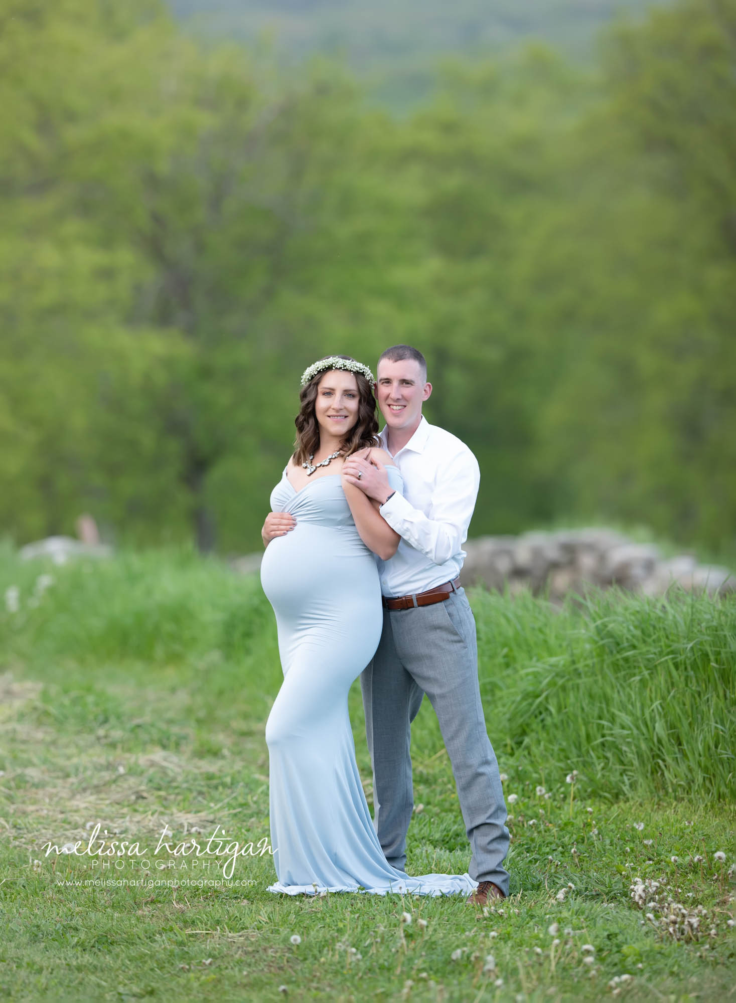 mom dad holding baby bump mom wearing long light blue maternity gown with baby's breath flower wreath maternity photography Massachusetts Connecticut maternity photographer capturing couple from Holland Massachussets
