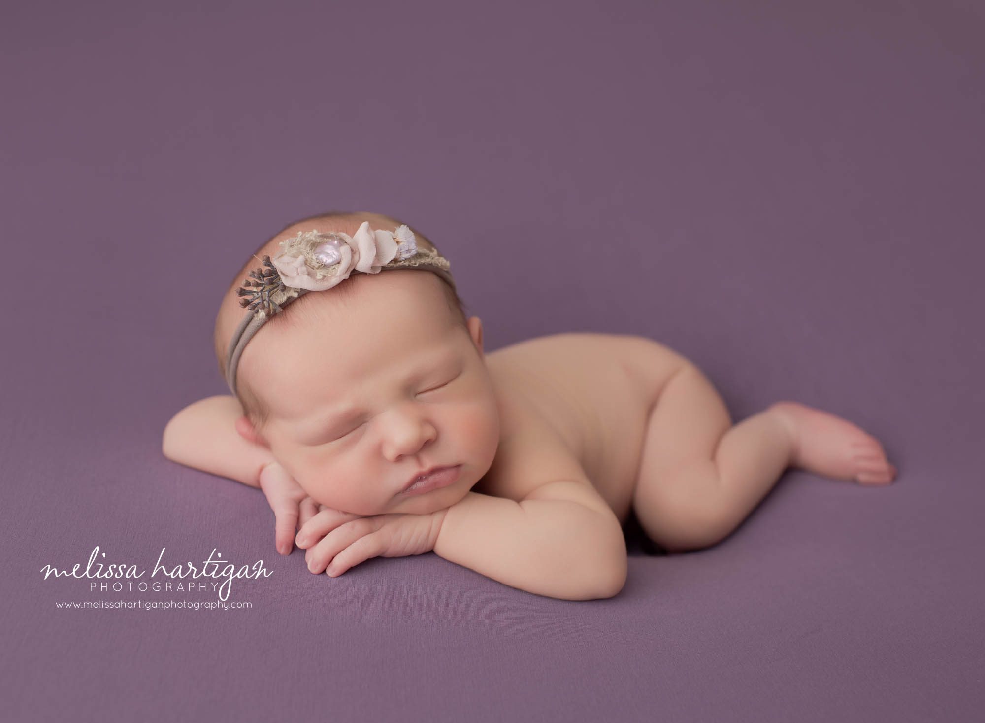 newborn baby girl posed on side with chin on hands laying on her side with pretty girly headband newborn photographer Connecticut