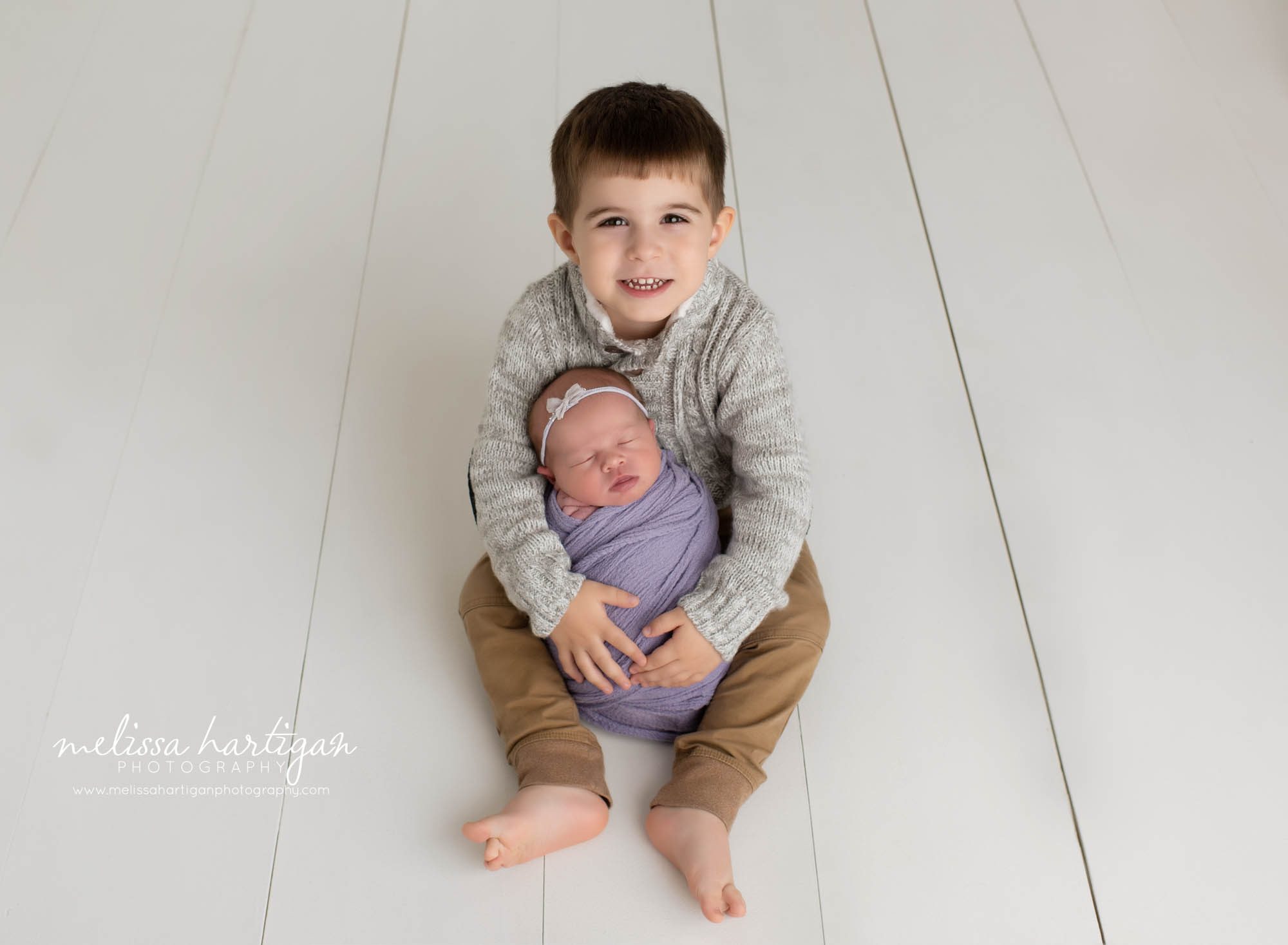 big brother holding newborn baby sister for sibling photo pose newborn photography session
