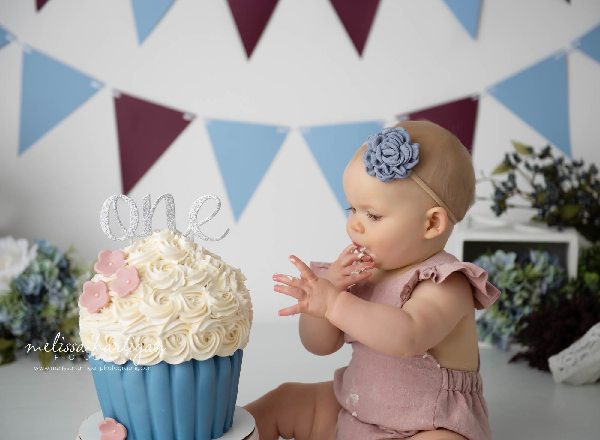 baby girl tasting cake off finger cake smash cake