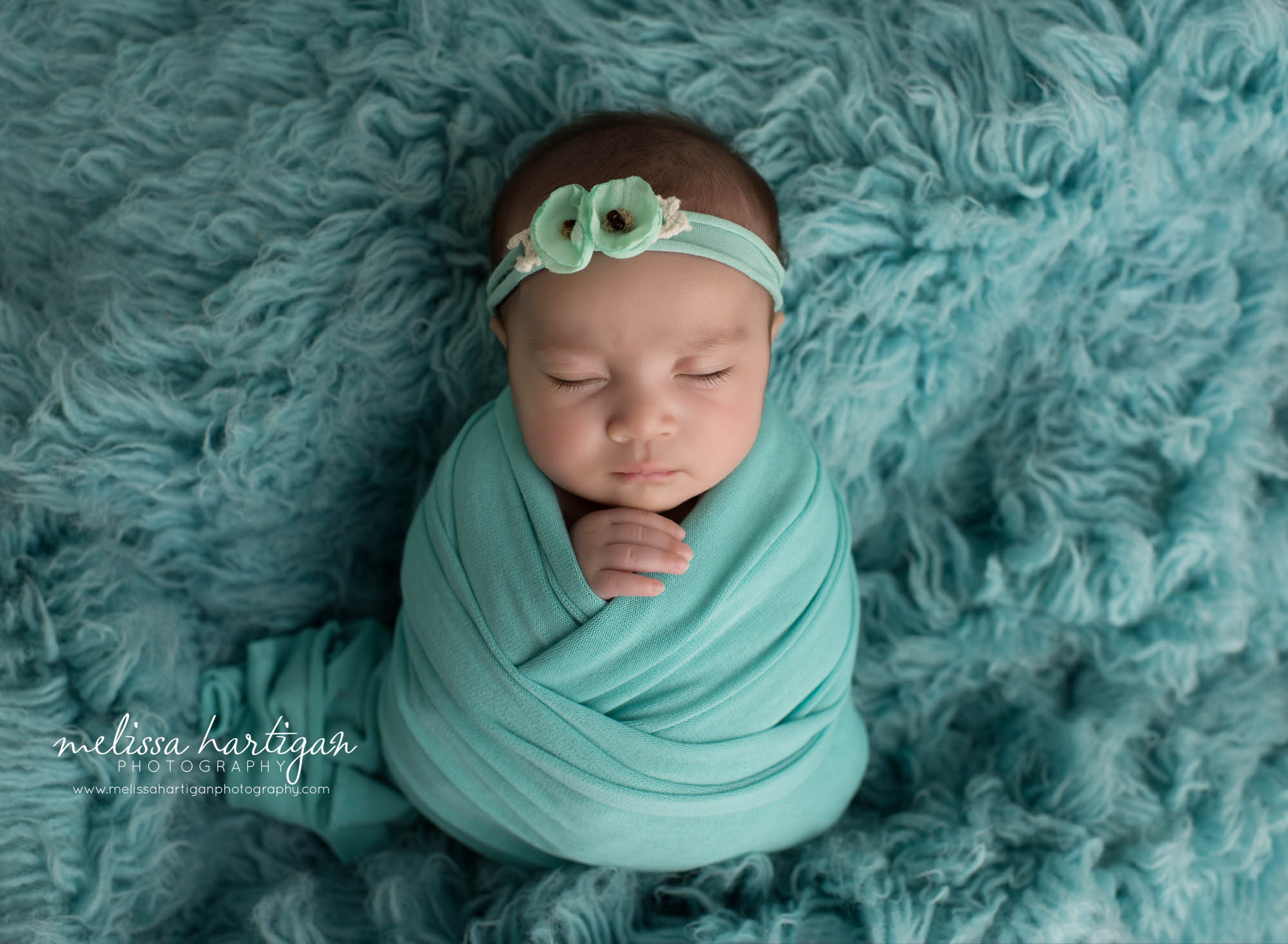 newborn baby girl wrapped in teal color with teal flower headband CT Newborn Phbotographer
