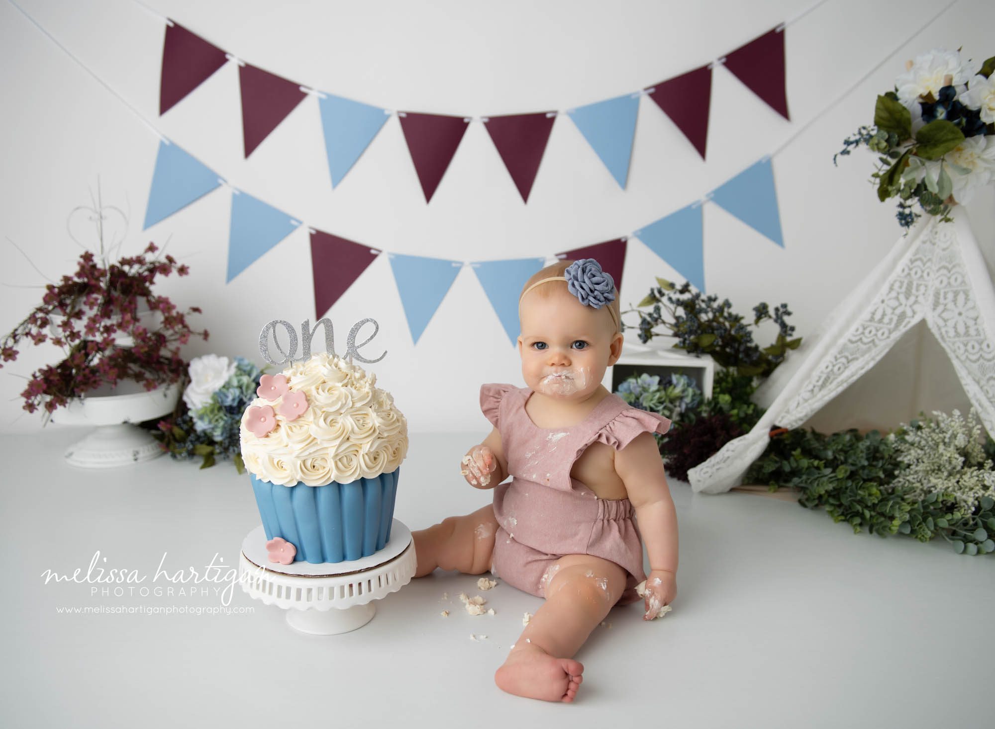 baby girl sitting on floor digging into cake smash cake blue and pink