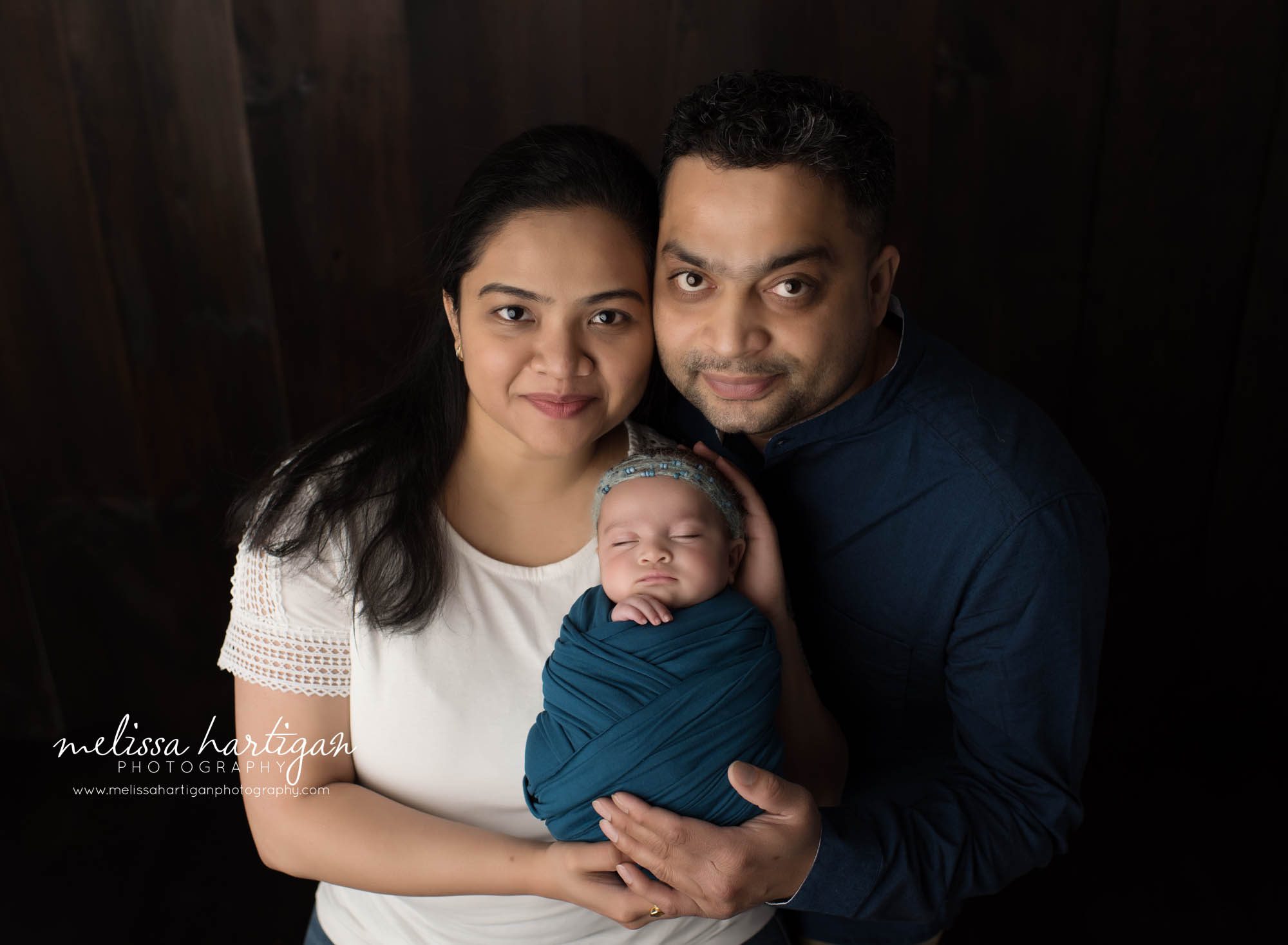newborn baby girl wrapped in blue posed with mom and dad holding their daughter Connecticut newborn photography
