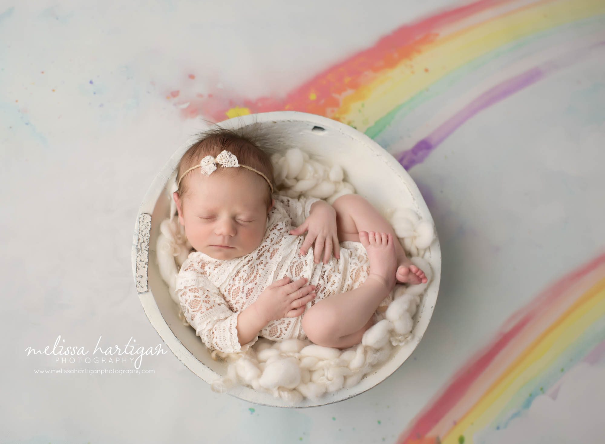 rainbow baby newborn set up with pastel water rainbow watercolors baby girl posed in wooden bowl