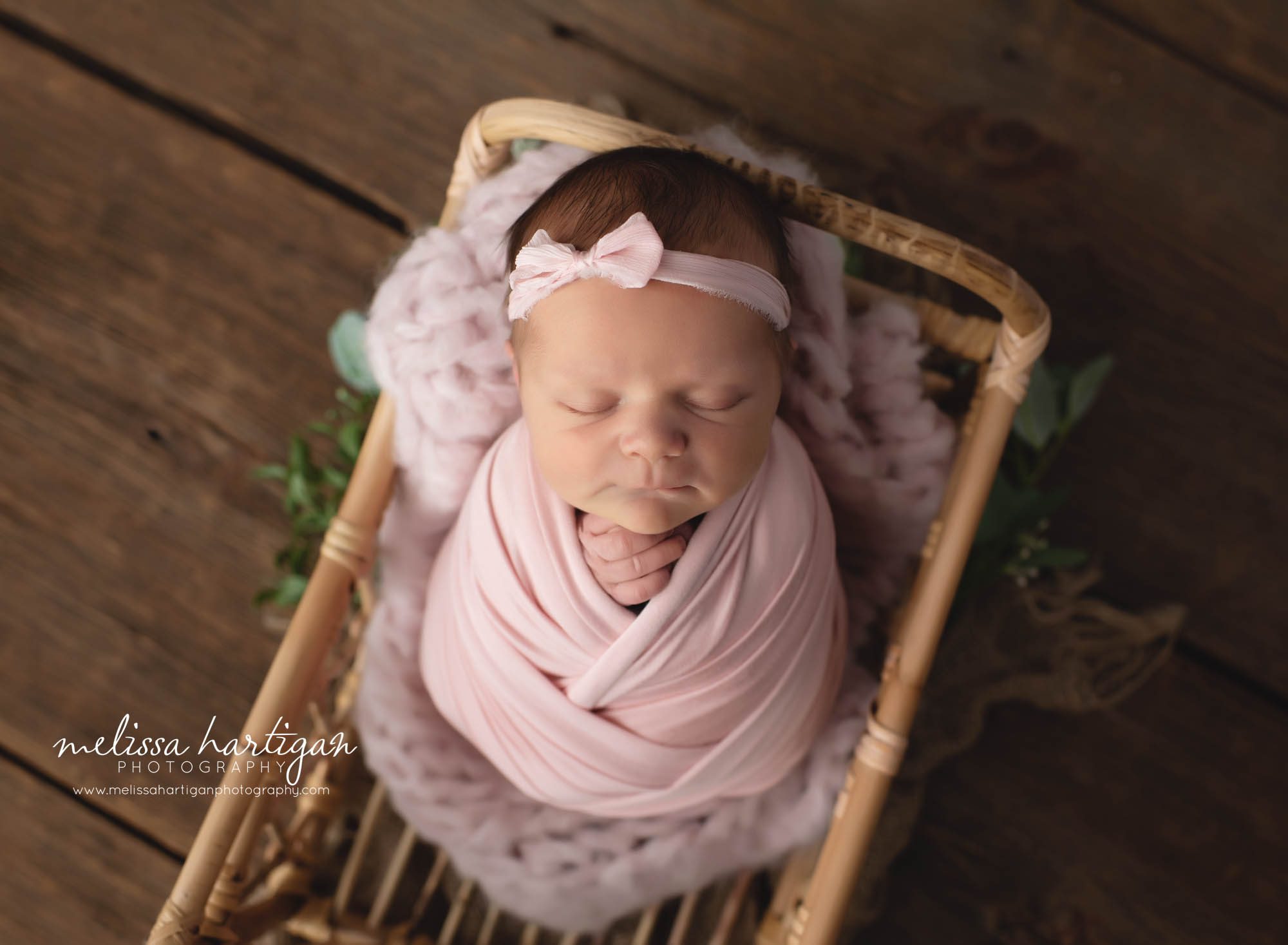 newborn baby girl wrapped in light pink wrap with pink bow headband hartford county newborn photographer CT