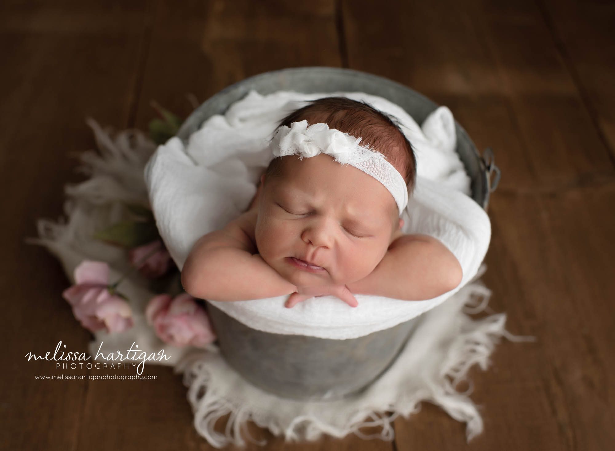 newborn baby girl posed in metal bucket with white and pink flowers hartford county newborn photographer