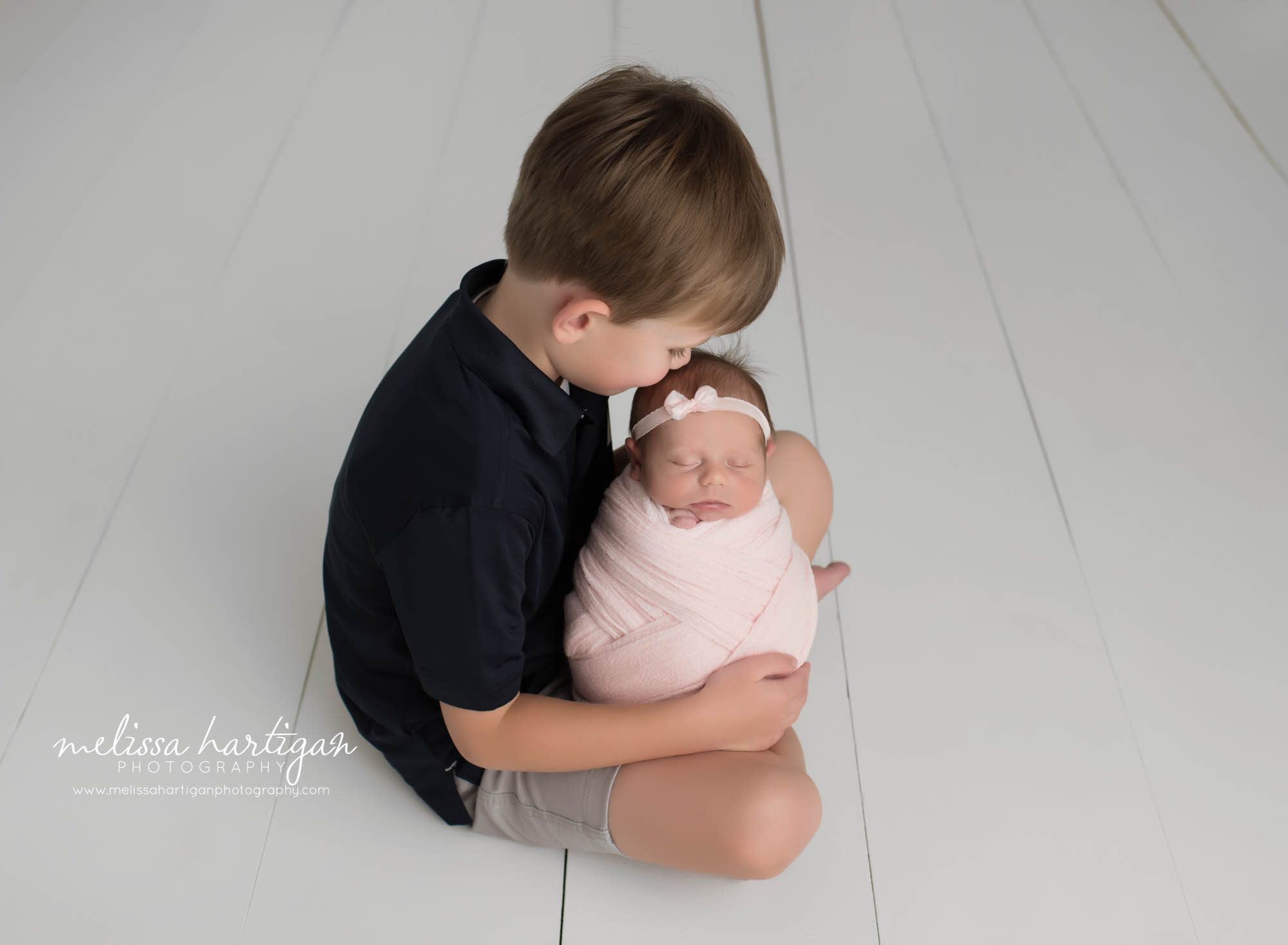 big brother holding baby sister kissing her on head MA newborn Photographer