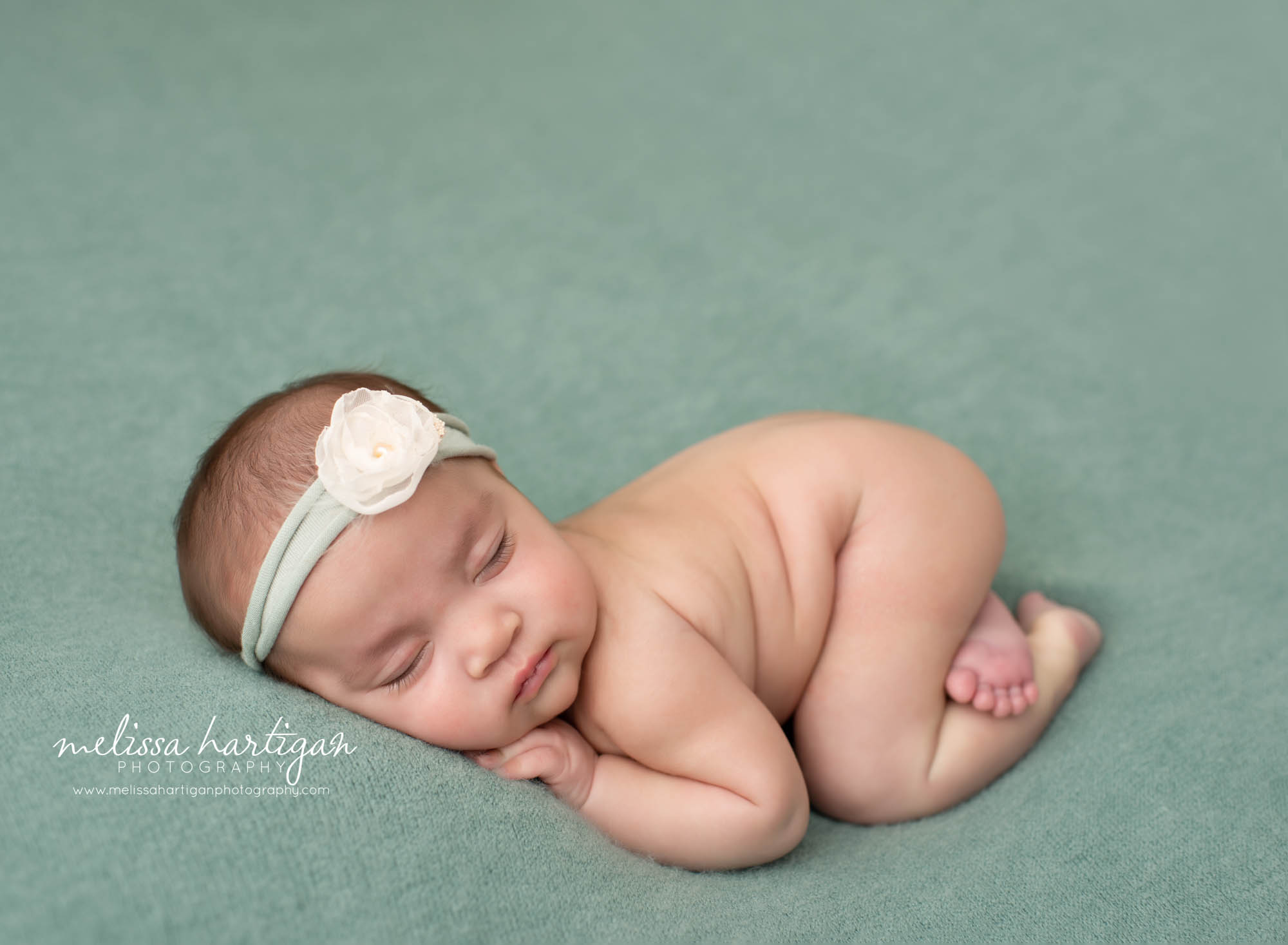 newborn baby girl posed on tummy with teal green colored flower headband Windsor newborn Photography Connecticut