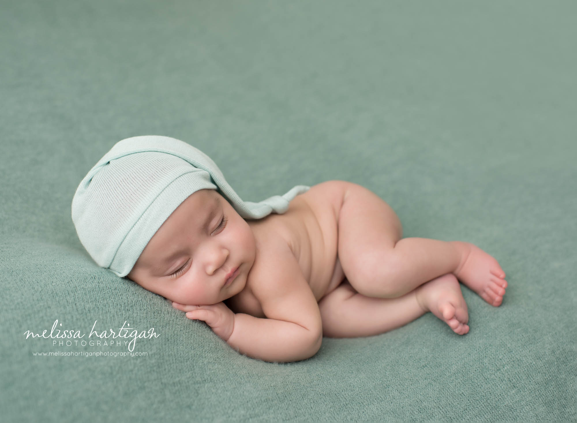 newborn baby girl posed on side teal green backdrop with light teal green sleepy cap Windsor newborn Photography Connecticut