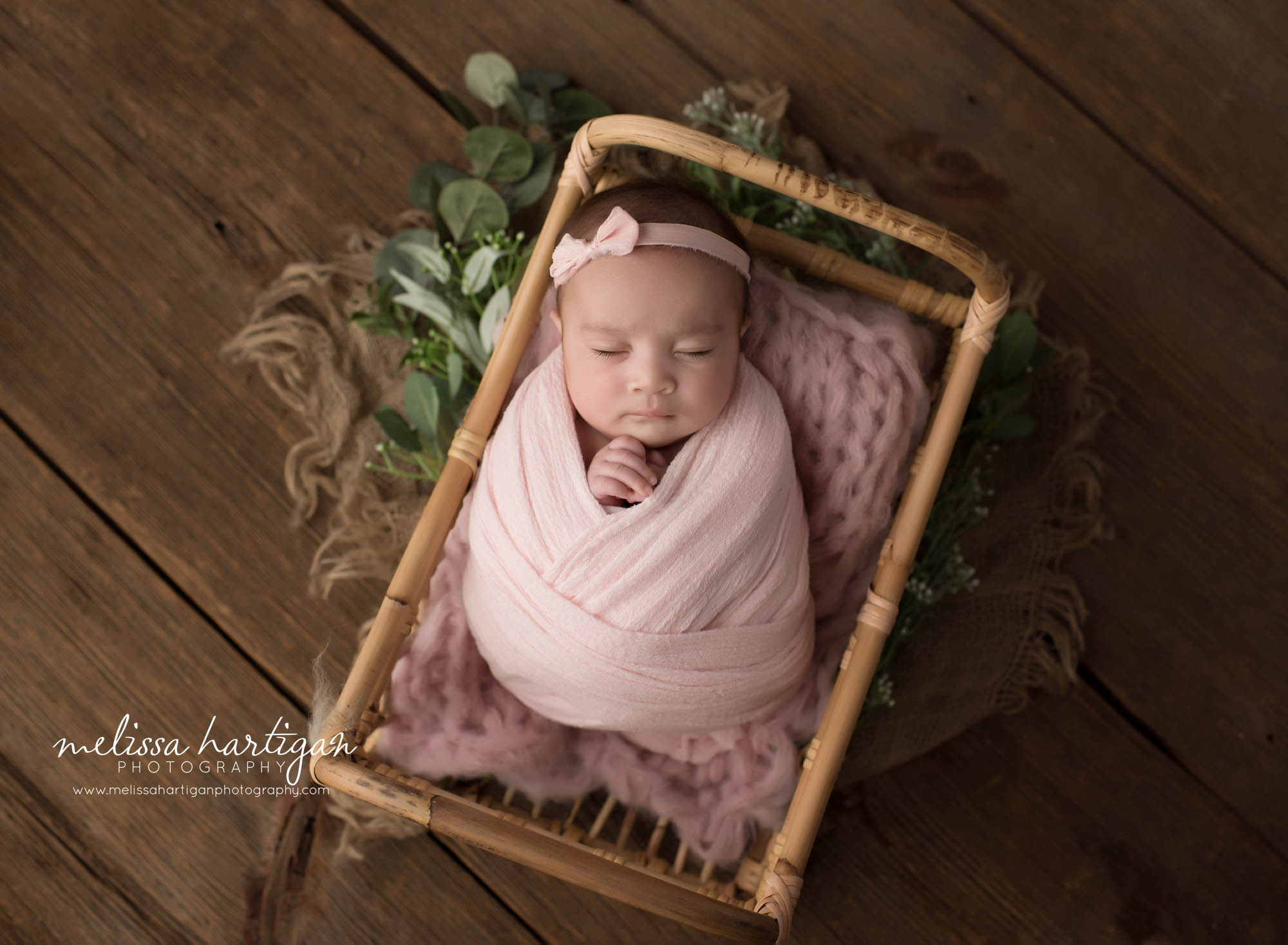 Newborn baby girl wrapped in light pink wrap with green foilage elements windsor newborn photographers