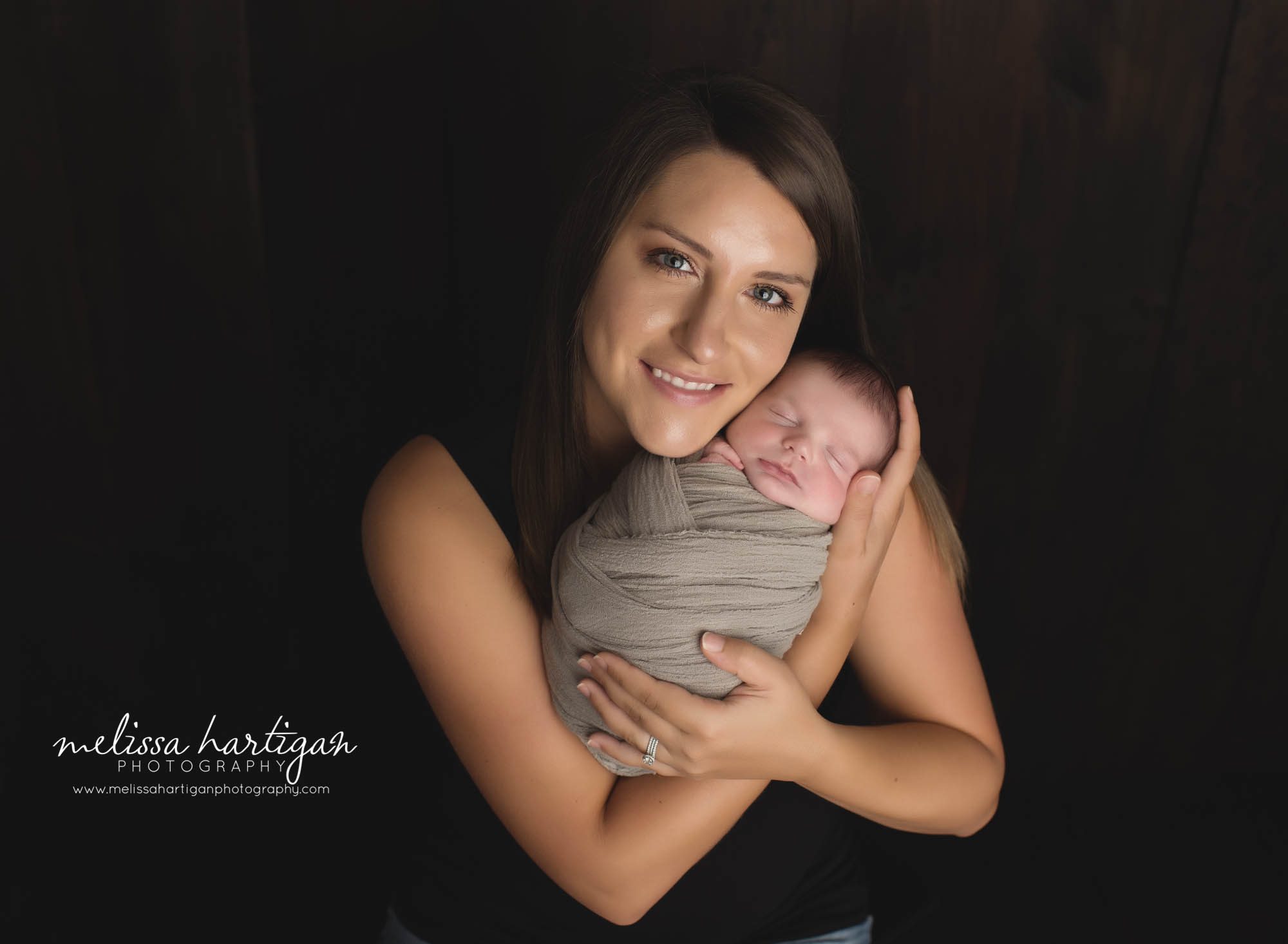 mom holding newborn son wrapped studio newborn photography