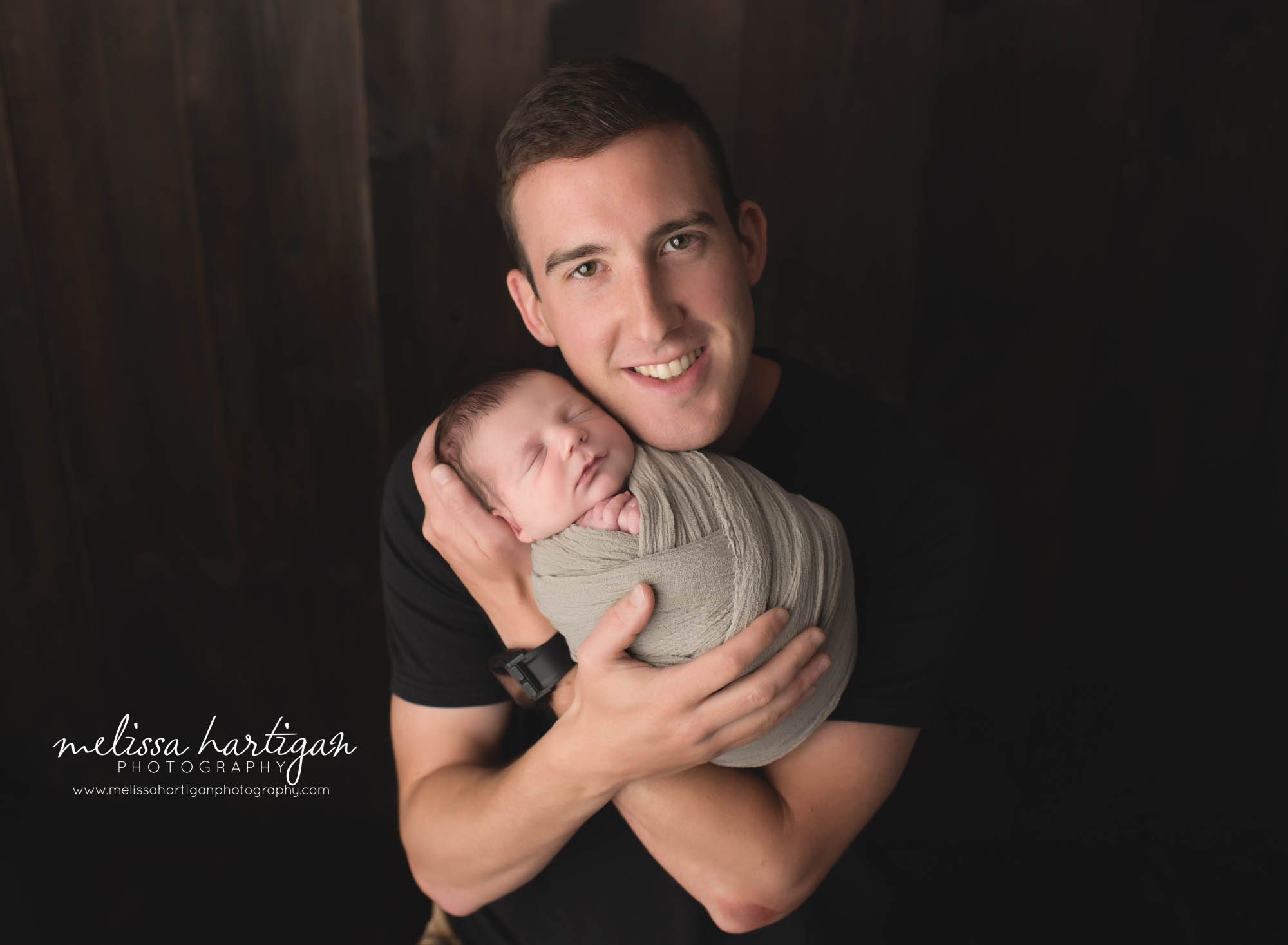 dad holding newborn son wrapped studio newborn photography