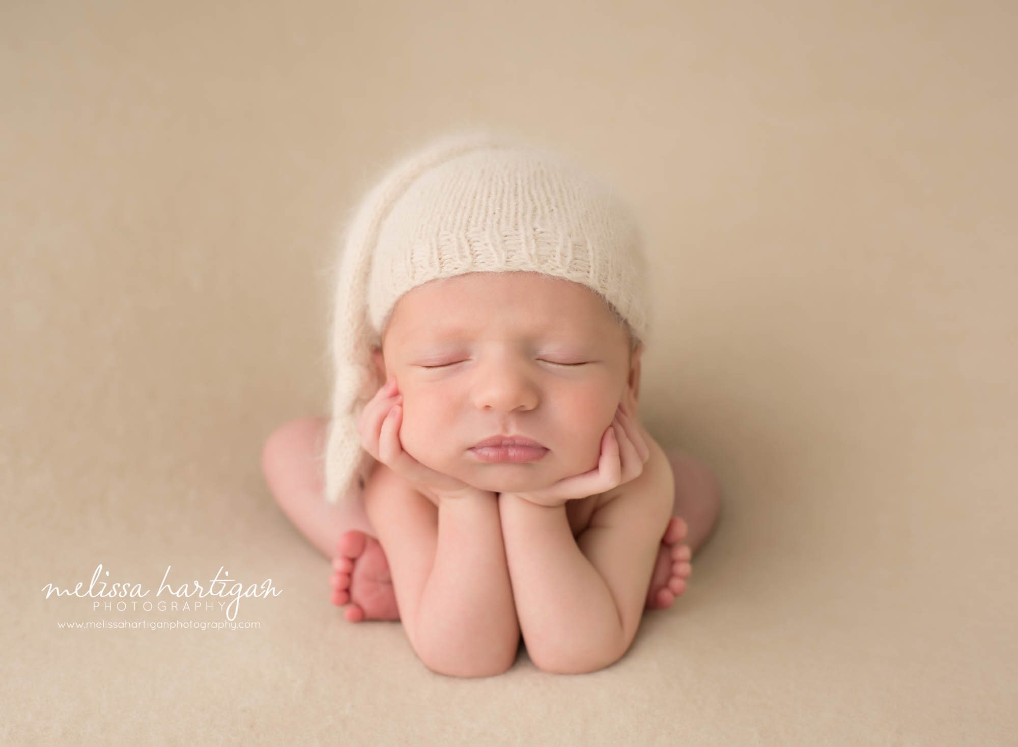 newborn baby boy posed froggy pose with knitted sleepy cap