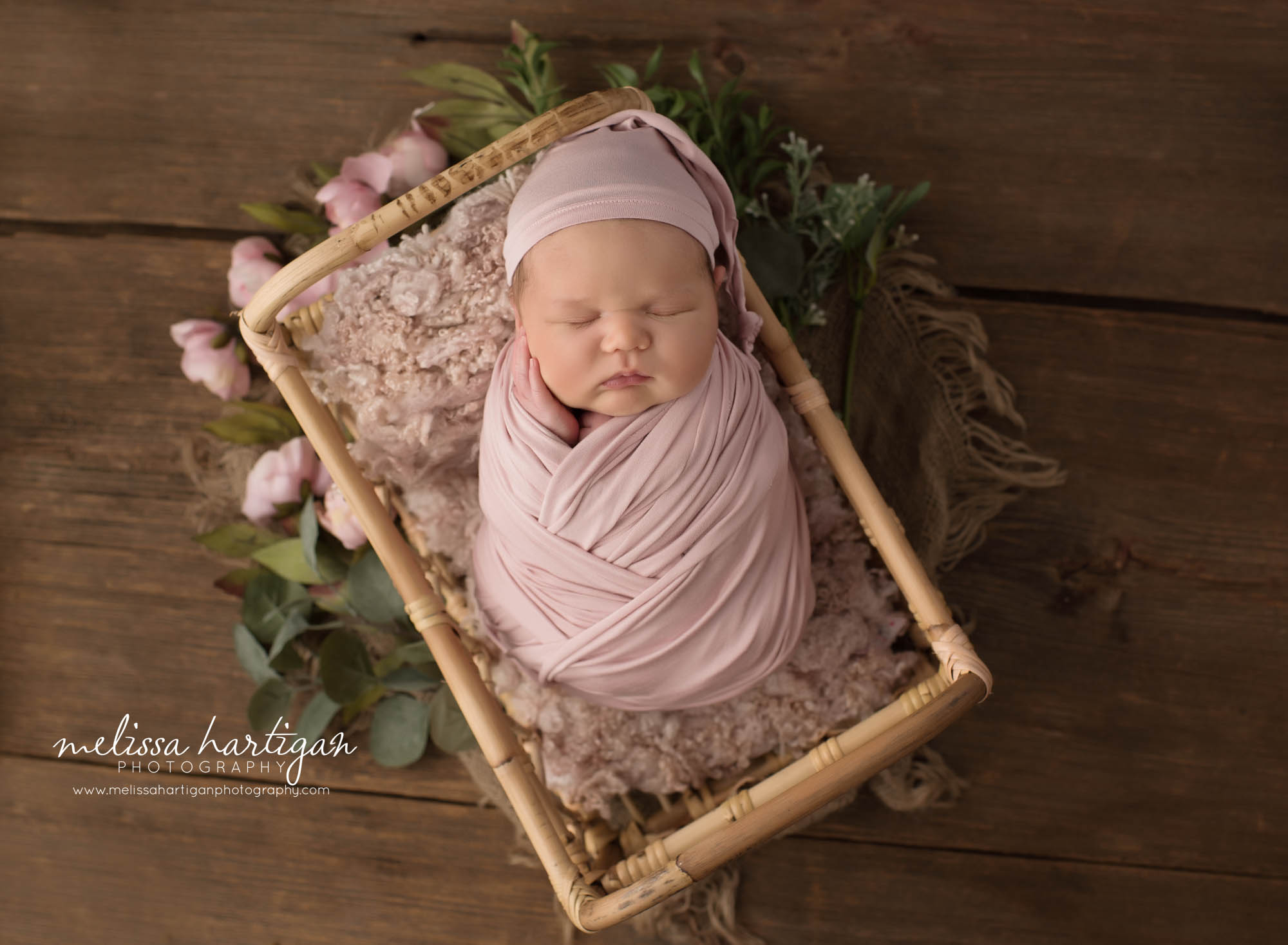 Newborn baby girl wrapped in mauve pink colored wrap with matching sleepy cap posed in basket CT newborn Photography Tolland Country