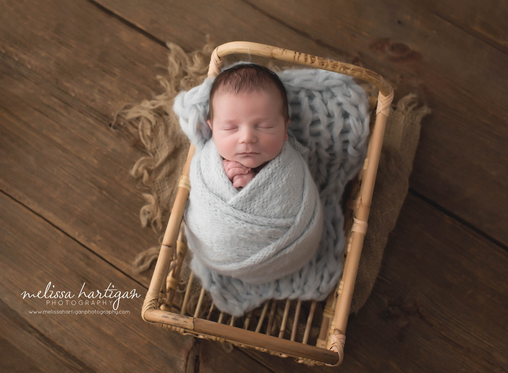 Newborn baby boy wrapped in gray wrap posed in basket connecticut newborn photographer