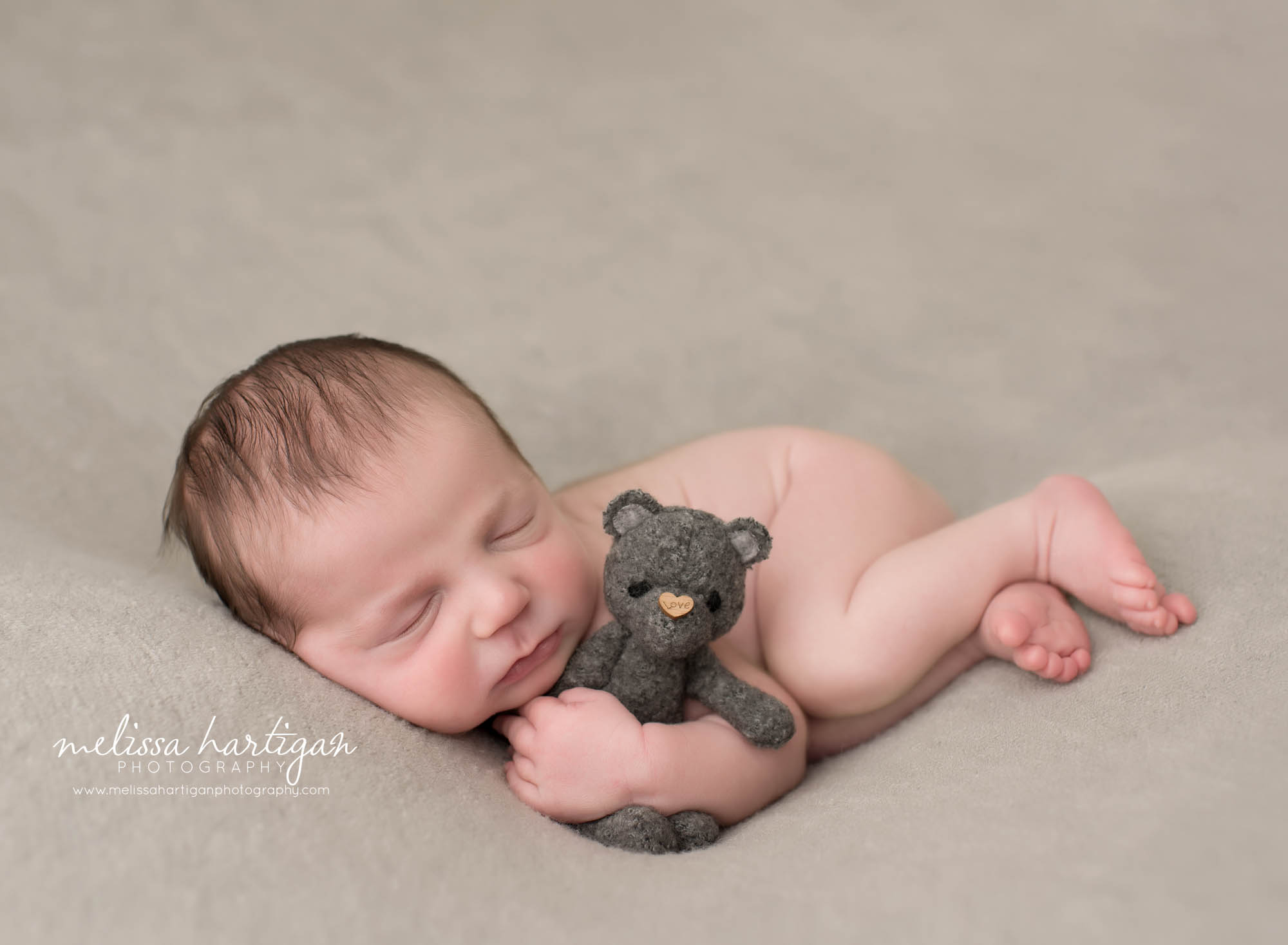 newborn baby boy posed on side with gray teddy bear MA newborn photographer