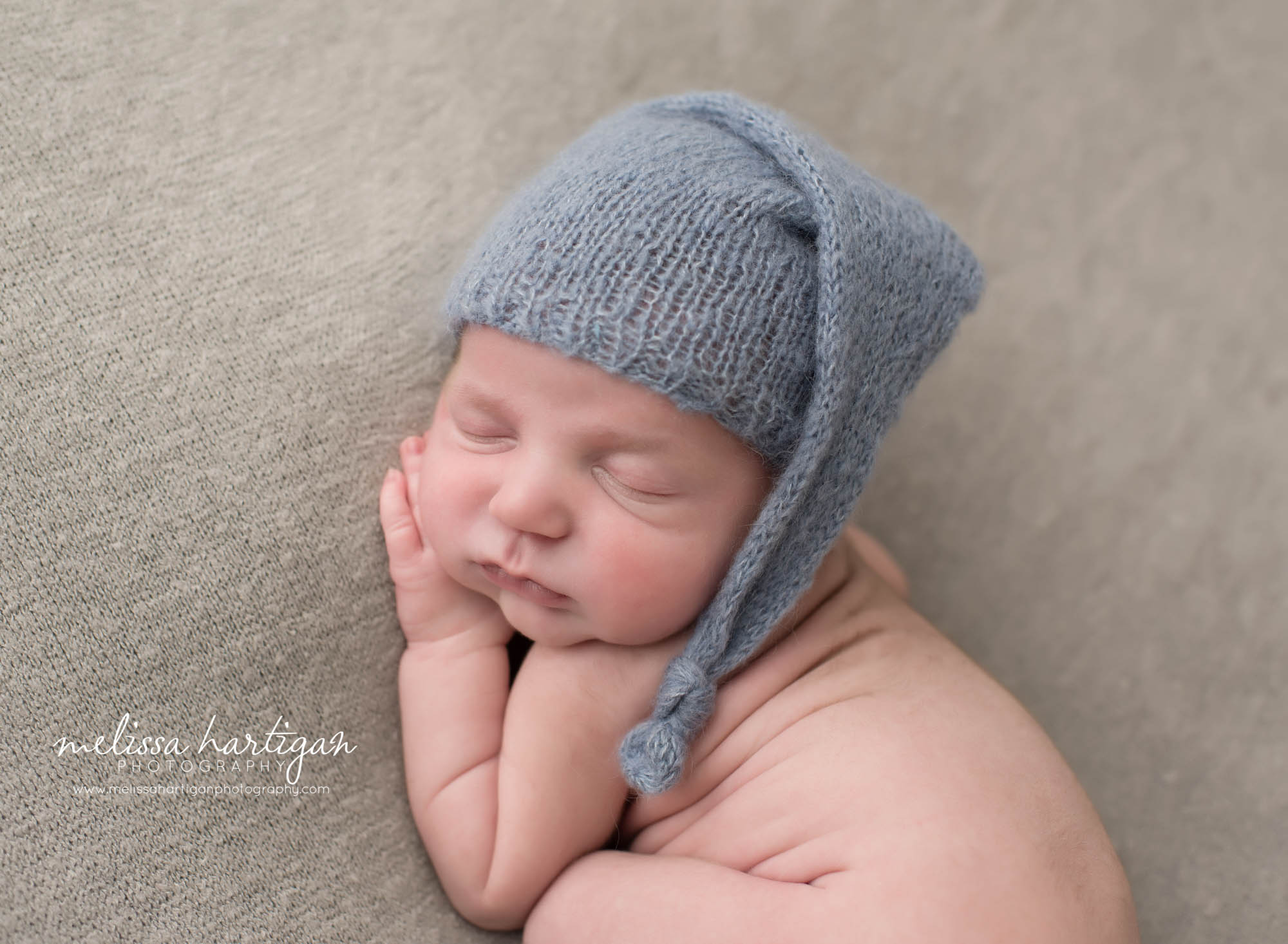 newborn baby boy posed on side with blue knitted sleepy cap baby photography MA