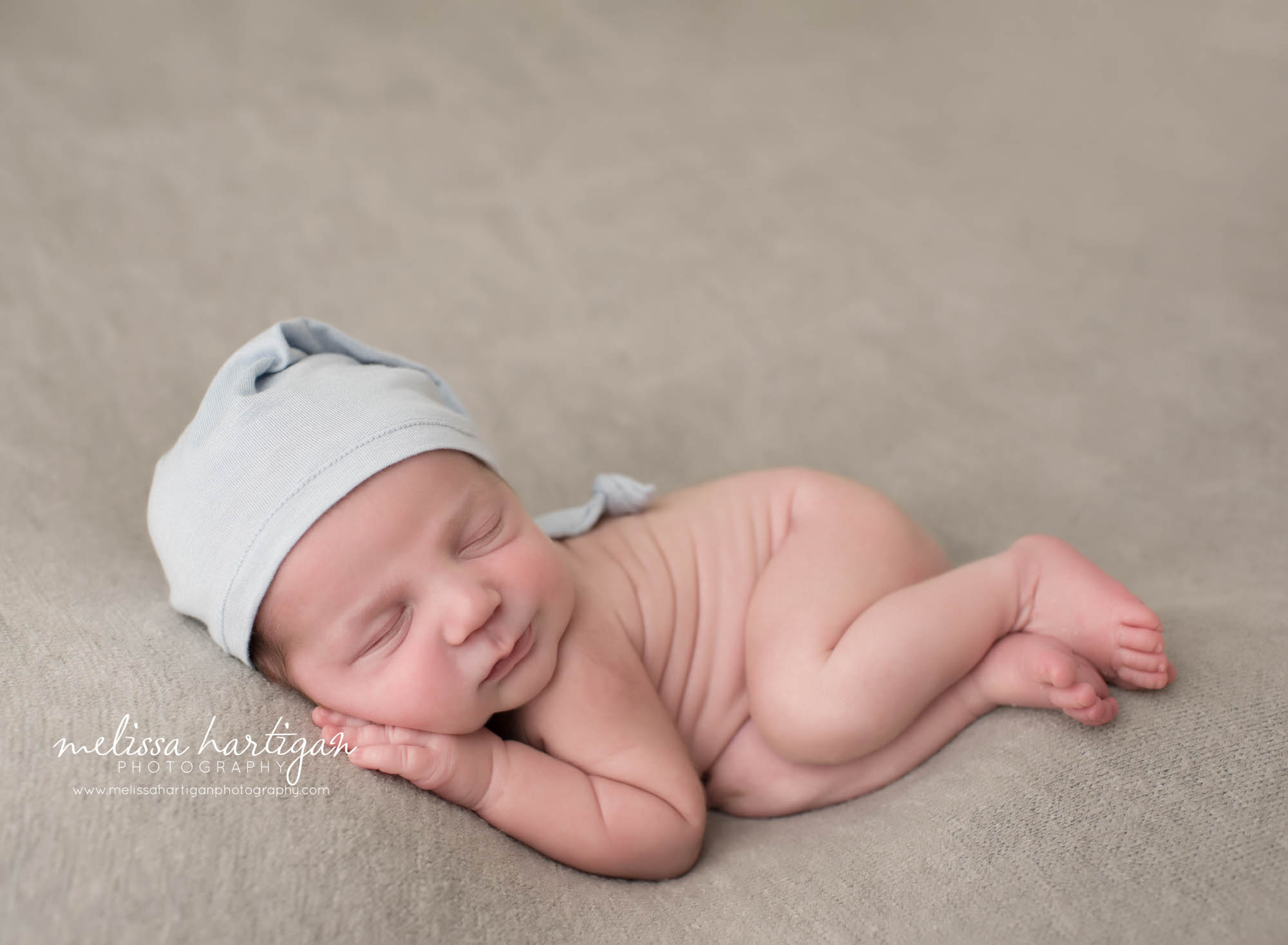 newborn baby boy pose don side with light blue sleepy cap Massachusetts newborn photography