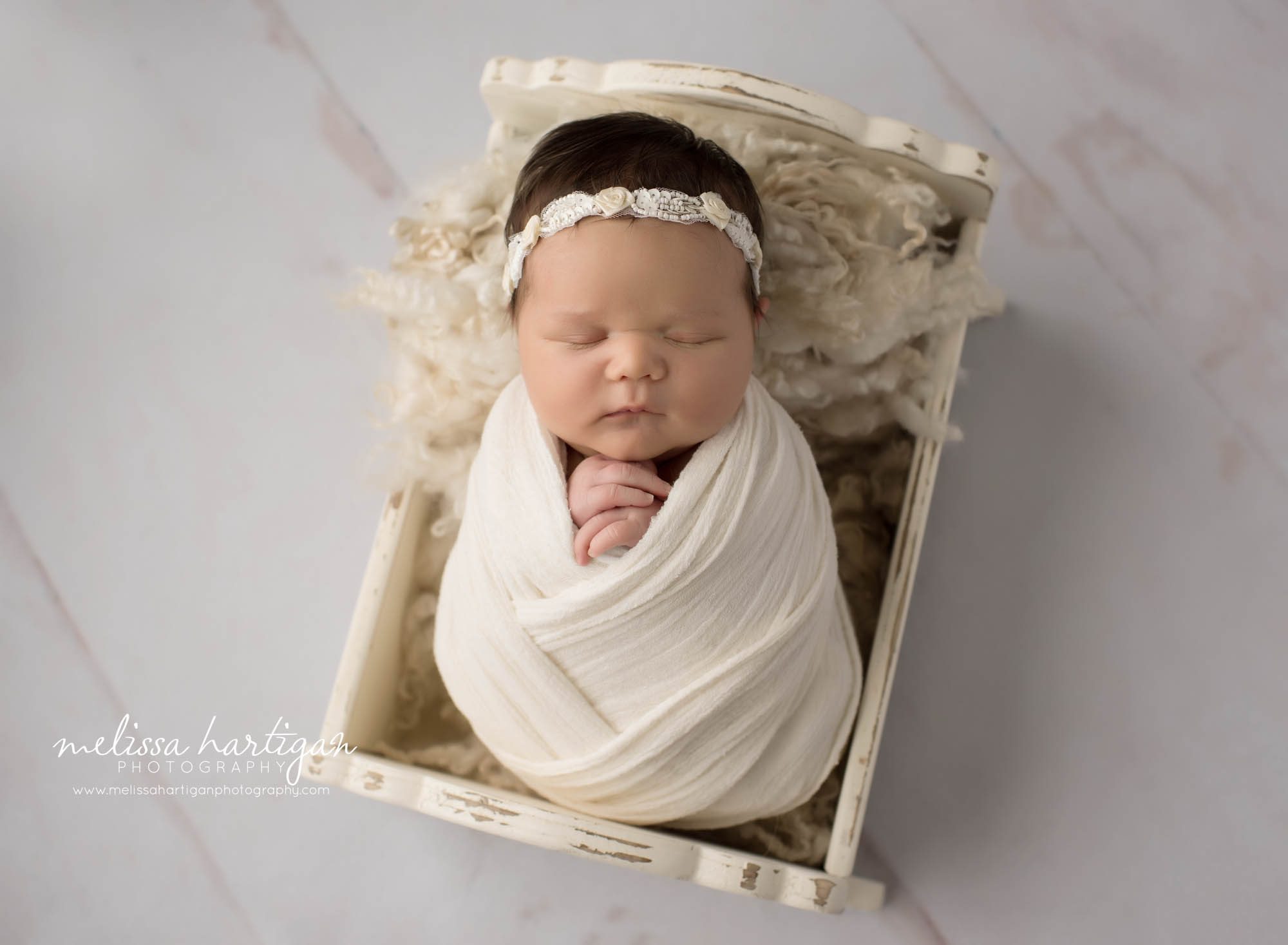 Newborn baby girl wrapped in cream color wrap posed in craddle Newborn Photography tolland county CT