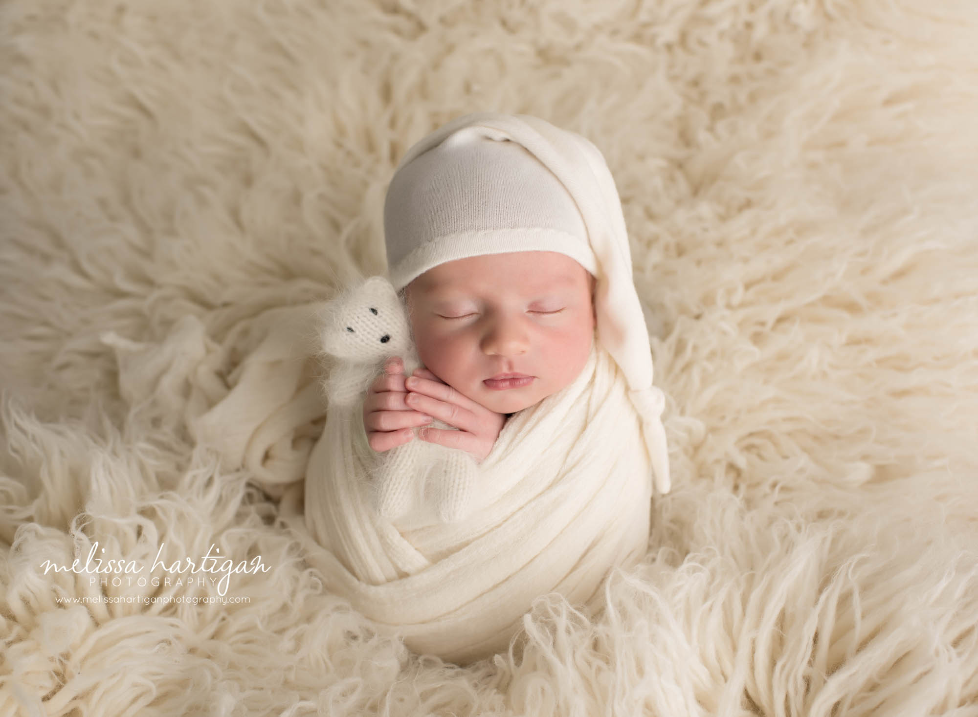 newborn baby boy wrapped in cream color with cream knitted with teddy bear and cream sleepy cap