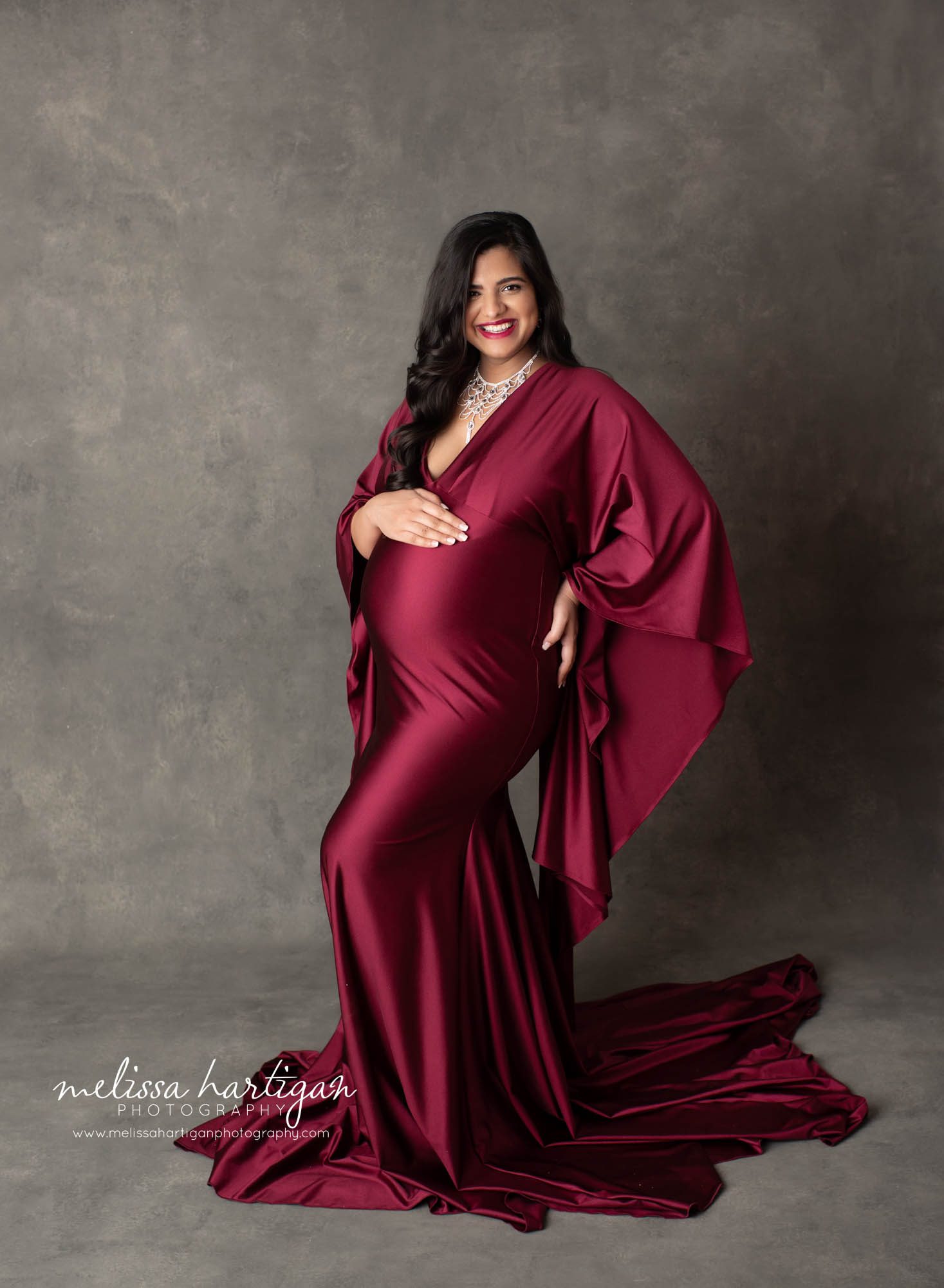 Pregnant mom standing maternity pose mom wearing red jewel toned form fitting maternity gown CT maternity Photographer