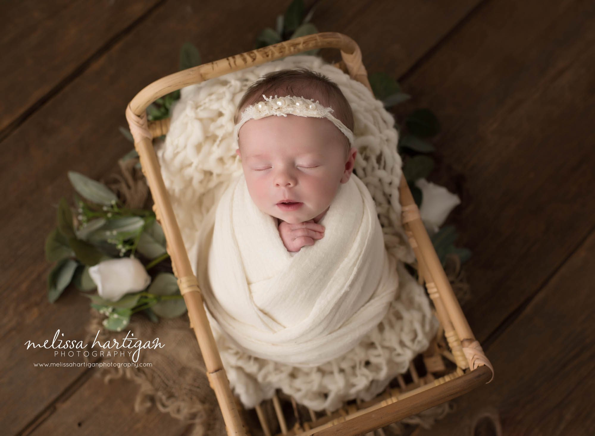 baby girl wrapped in cream wrap with cream newborn headband posed in basket