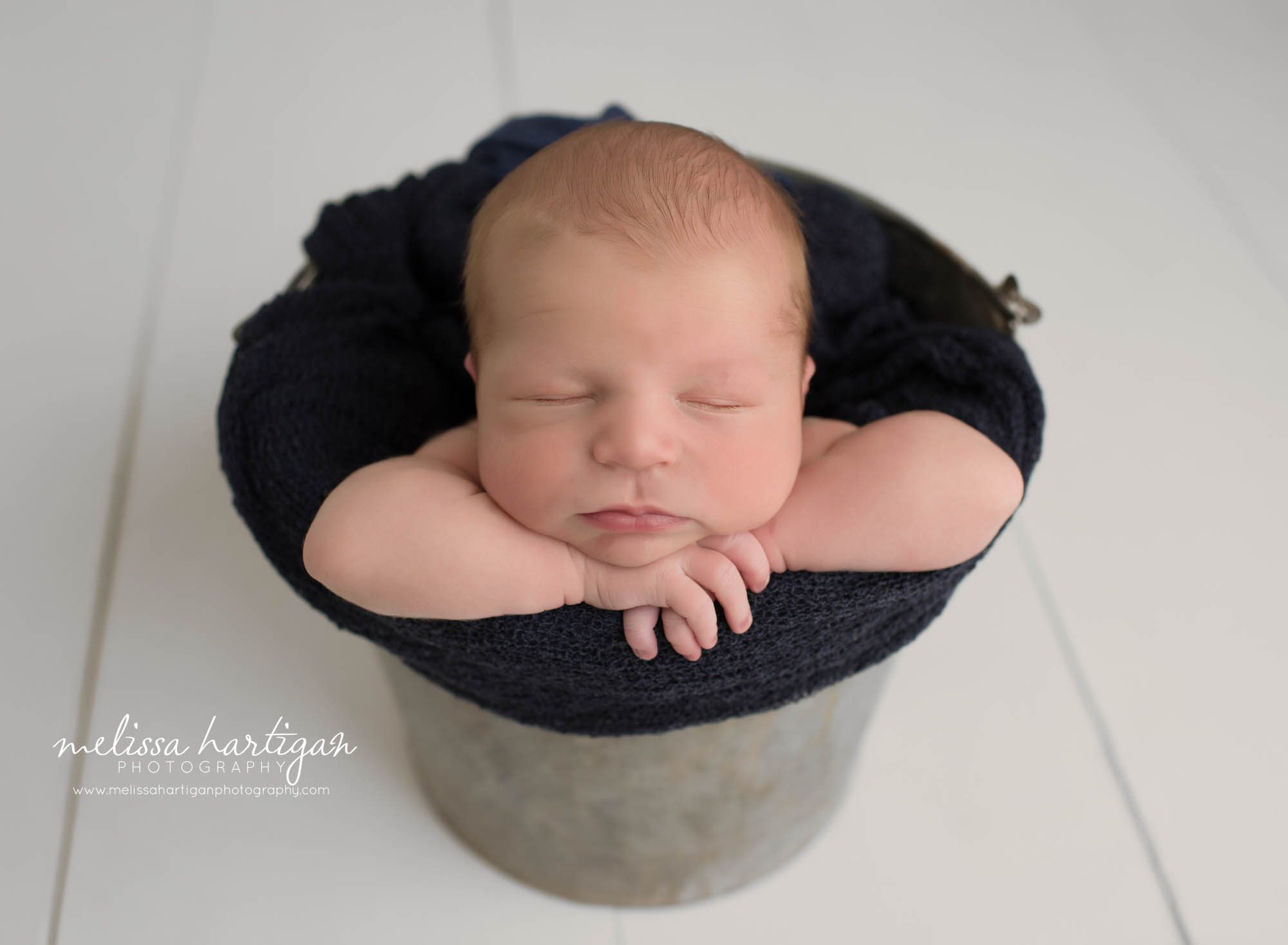 newborn baby boy posed in bucket with chin on hands CT newborn photographer