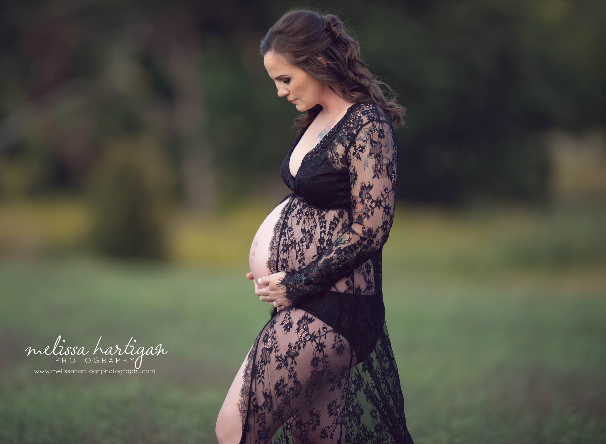pregnant mom to be looking down at baby bump holding belly with both hands CT maternity photographer