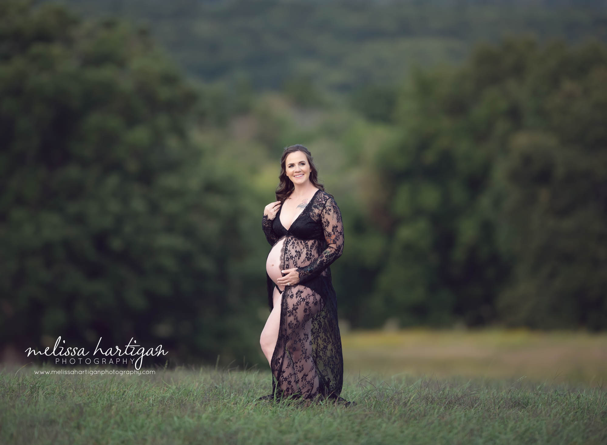 expectant mom holding belly and shoulder looking off to side smiling CT maternity Photography