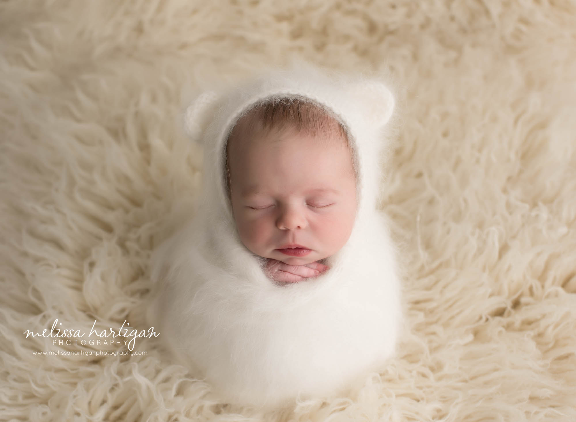 newborn baby girl wrapped in cream knitted wrap wearing bear bonnet CT baby photographer