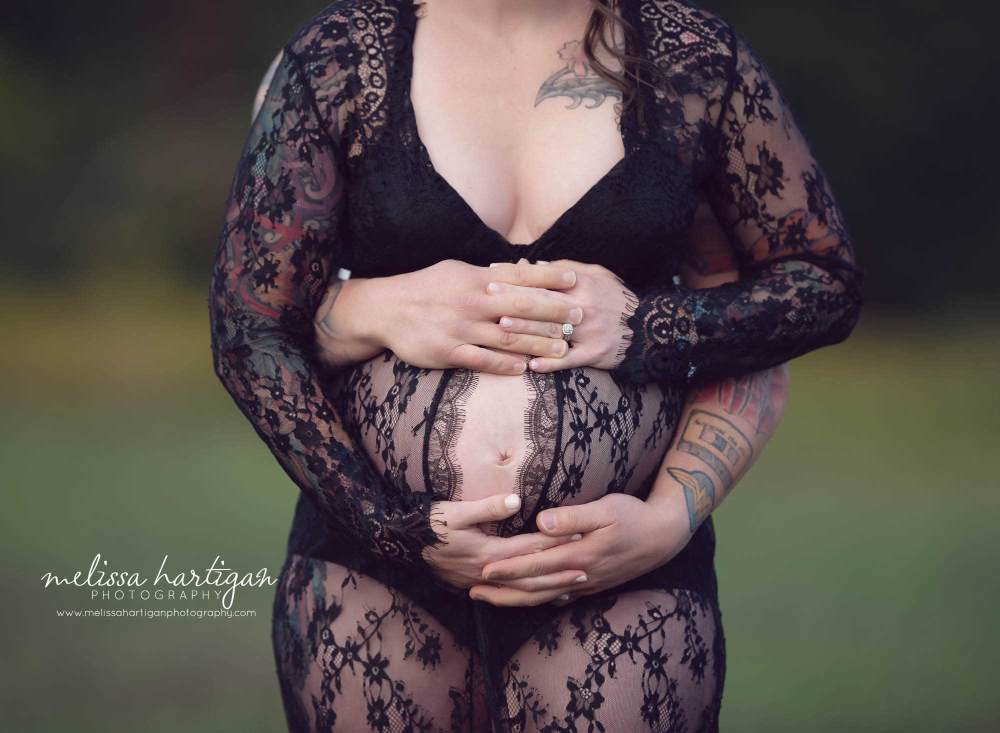 couples hands around pregnant baby belly