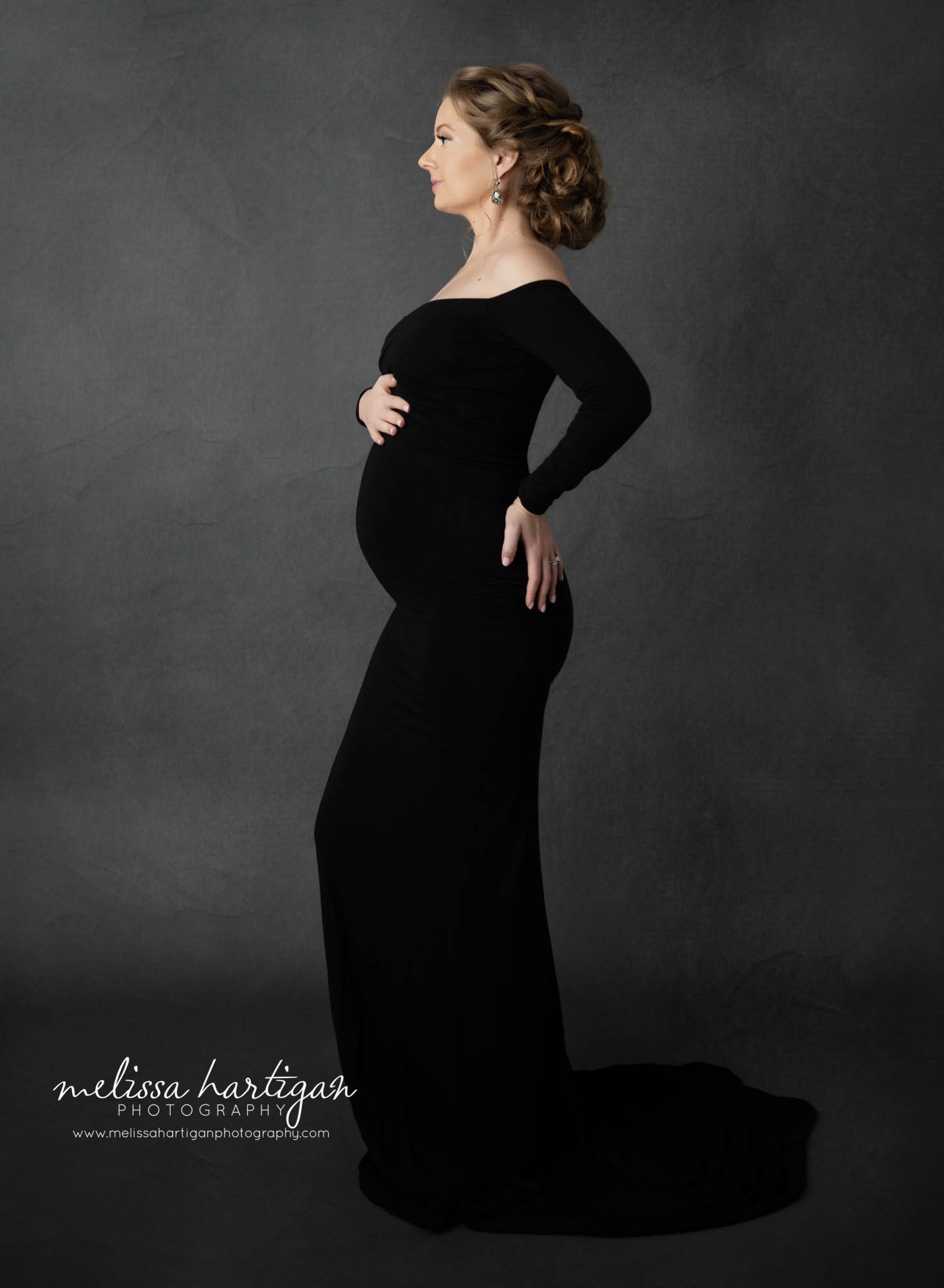 pregnant mom to be holding belly with hand on back looking forward west hartford maternity photography