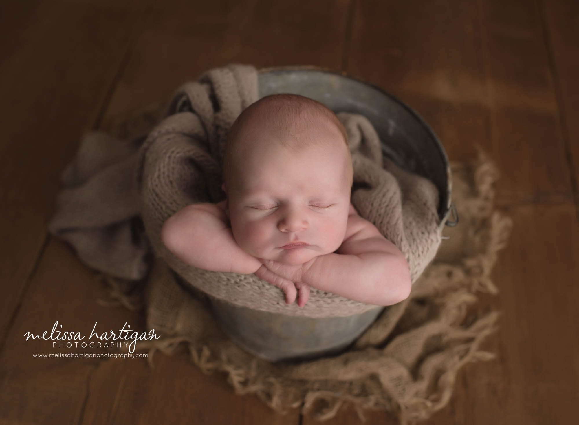 newborn baby boy posed in bucket with tna colored layer wrap cT newborn photography