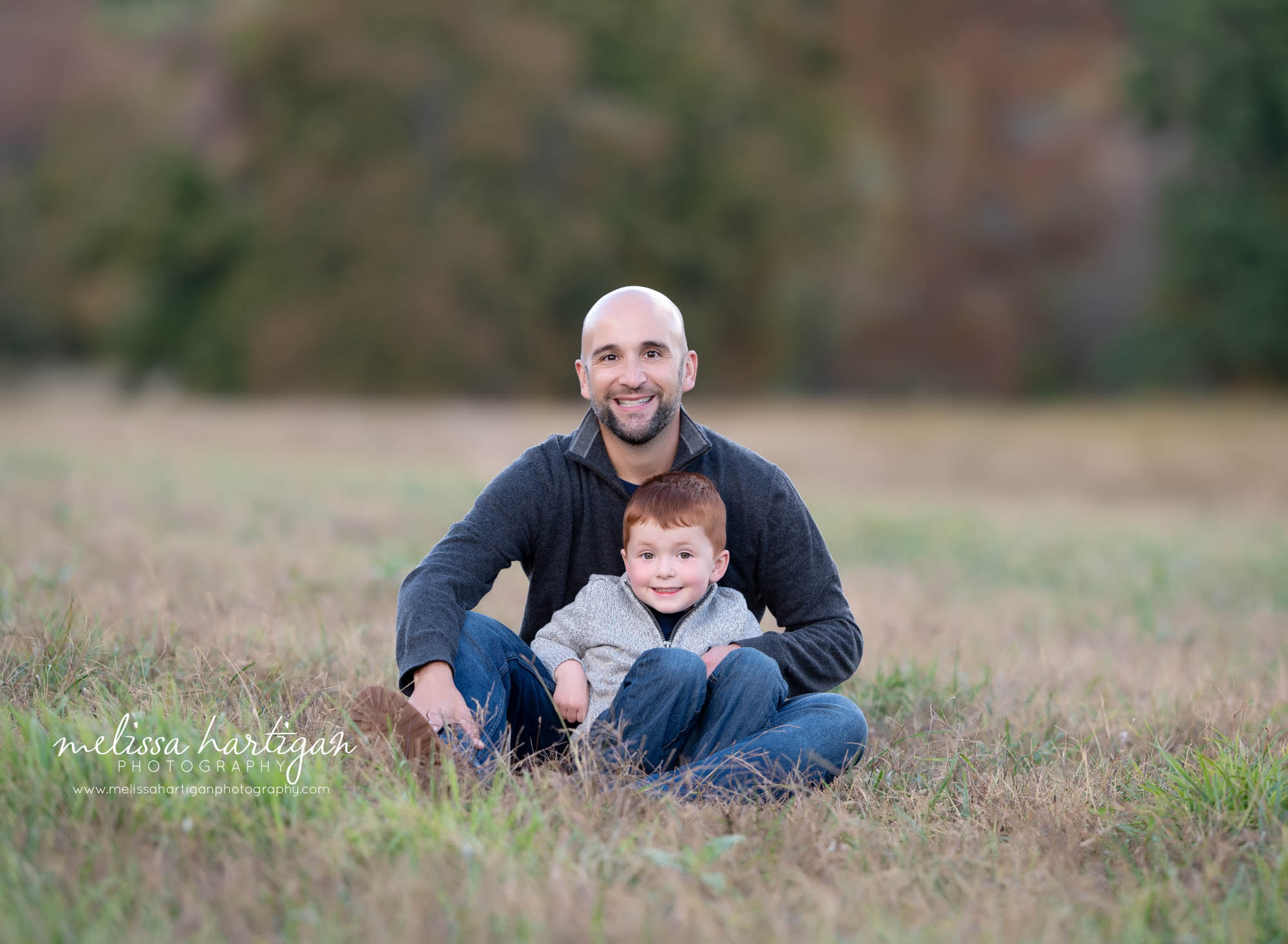 dad sitting on grass with son