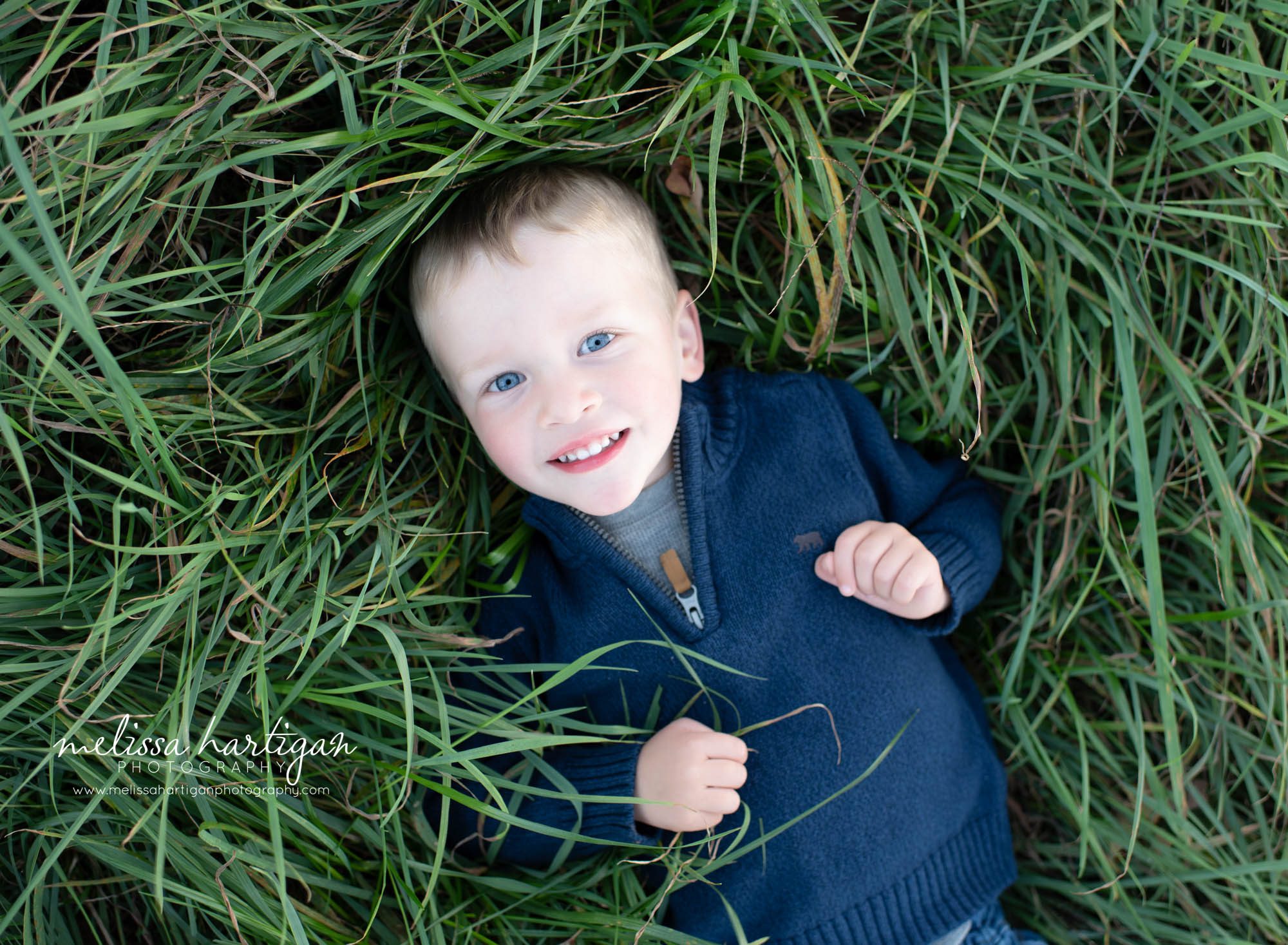 young boy laying in grass smiling