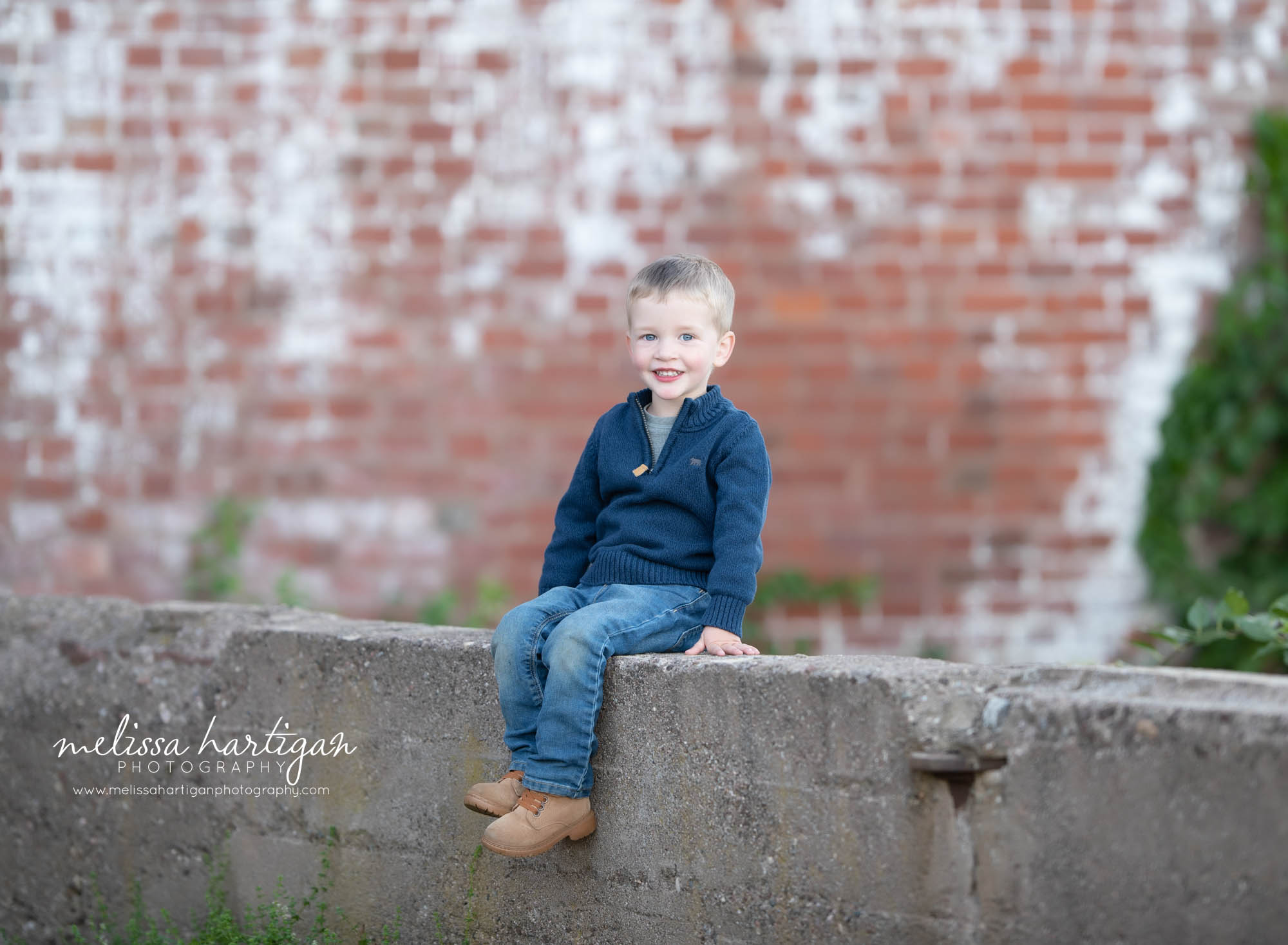 boy sitting on concrete wall