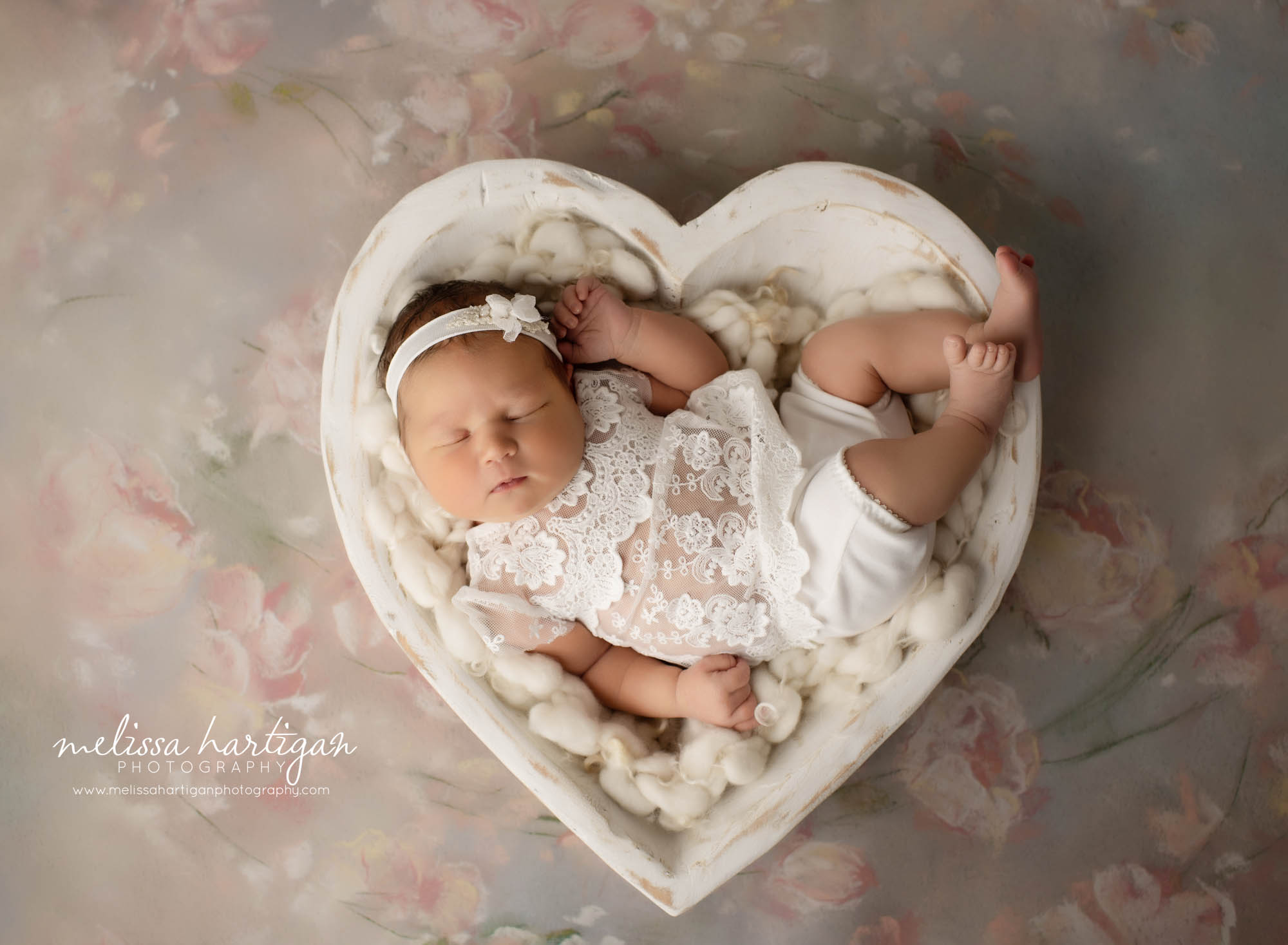 newborn baby girl posed in white wooden heart prop wearing lace outfit newborn photography hartford county