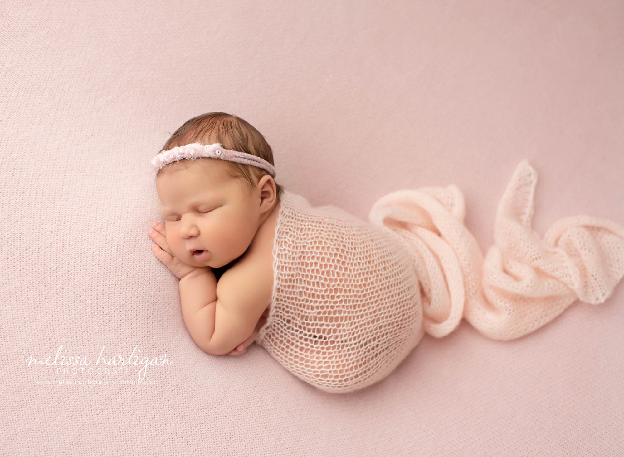 newborn baby girl posed on pink backdrop with knitted layer draped over newborn photography hartford county