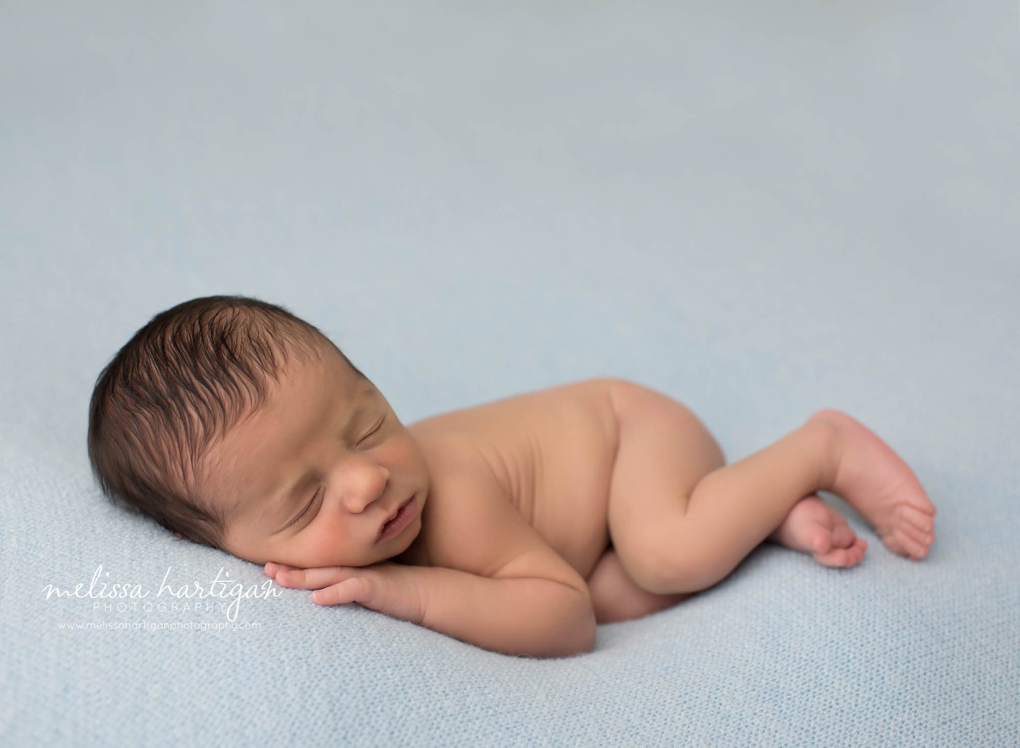 newborn baby boy posed on blue backdrop pose don side with hand under cheek newington CT newborn photography