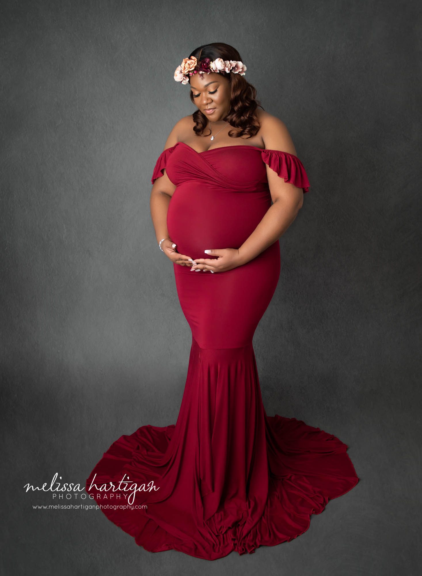 pregnant mom wearing long form fitting sweatheart neckline dress with flower crown studio maternity photography