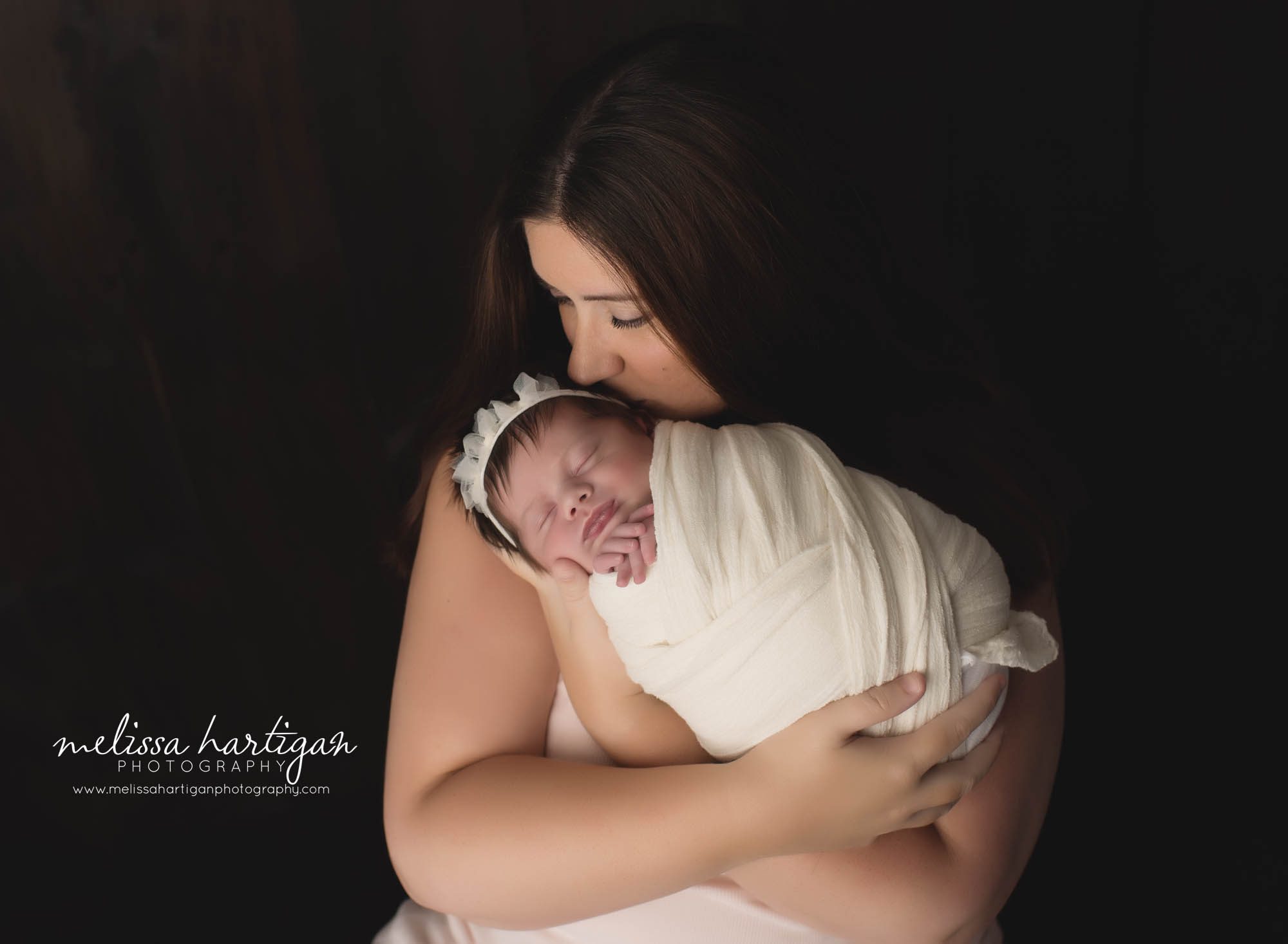mom kissing newborn daughter on head mom and baby pose