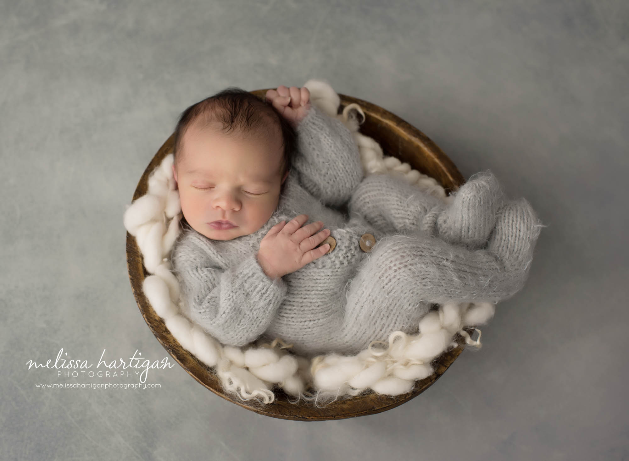 newborn baby boy wearing gray knitted footed newborn romper posed in wooden bowl sleeping peacefully North Haven CT baby photography