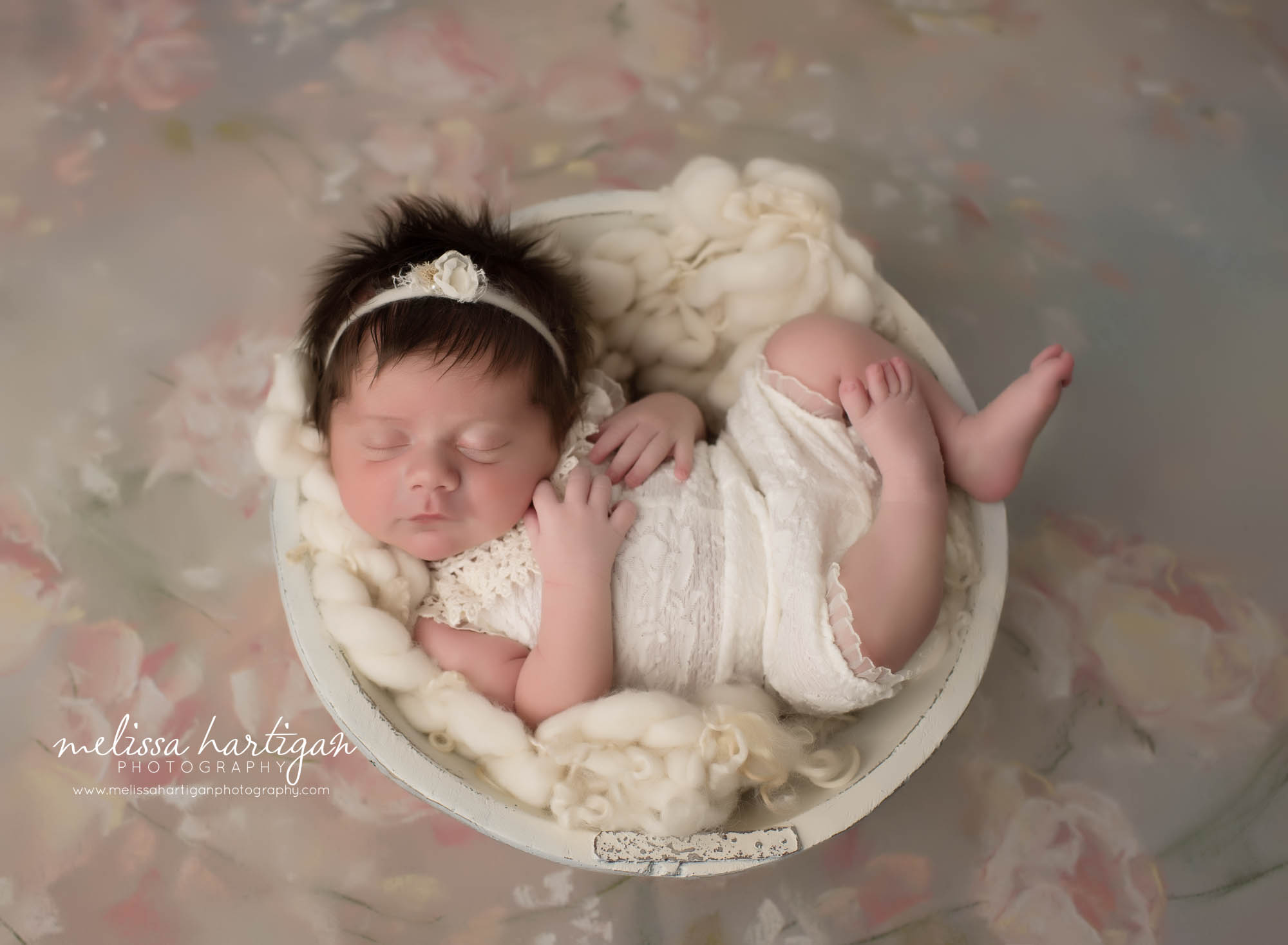 newborn baby girl posed in cream wooden bowl wearing cream newborn baby outfit
